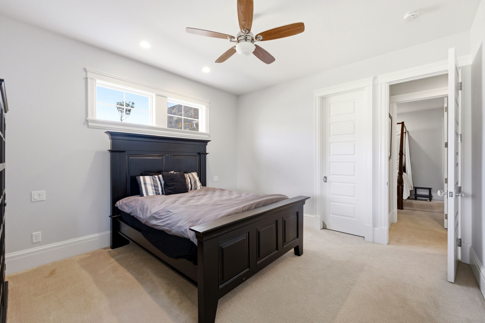 Recessed lighting illuminates neutral-toned carpeting, complemented by a ceiling fan with wood-finish blades