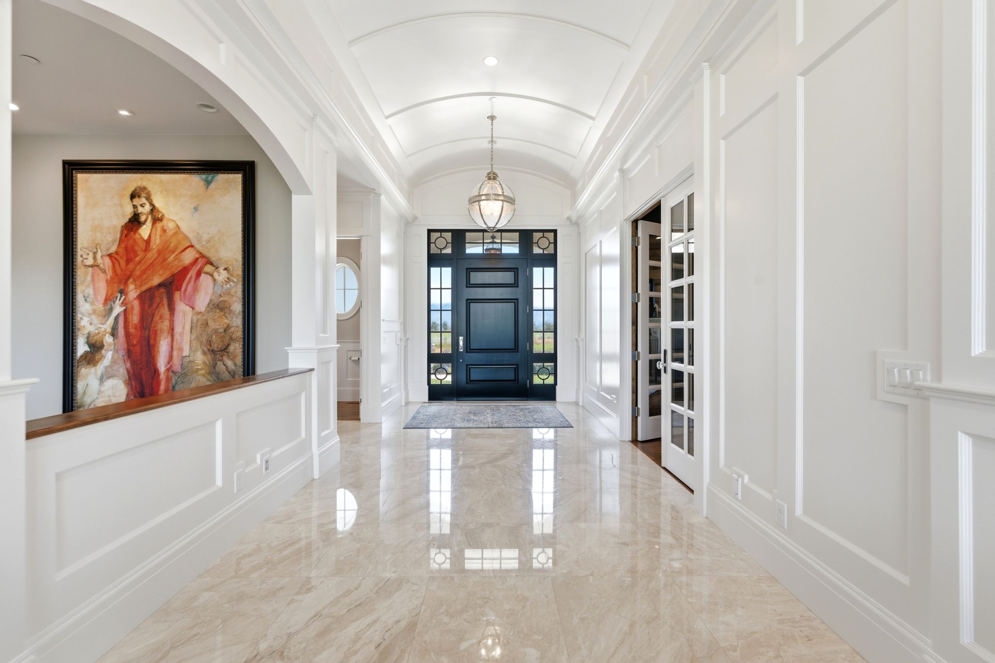 Grand entry hall featuring polished stone flooring and extensive white paneled wall detailing