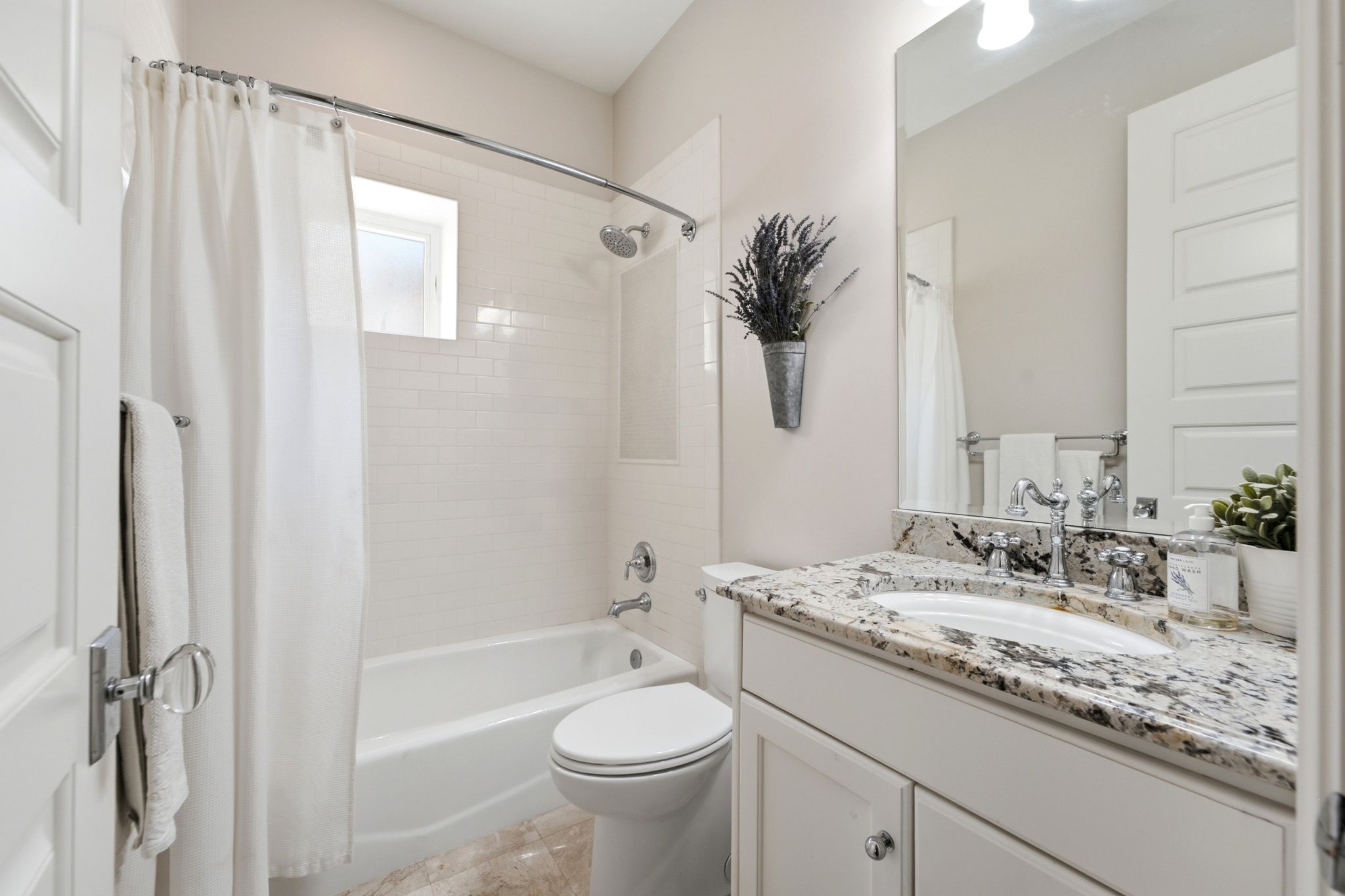 Bathroom featuring a white subway tile shower surround, a white porcelain bathtub, and a window with frosted glass