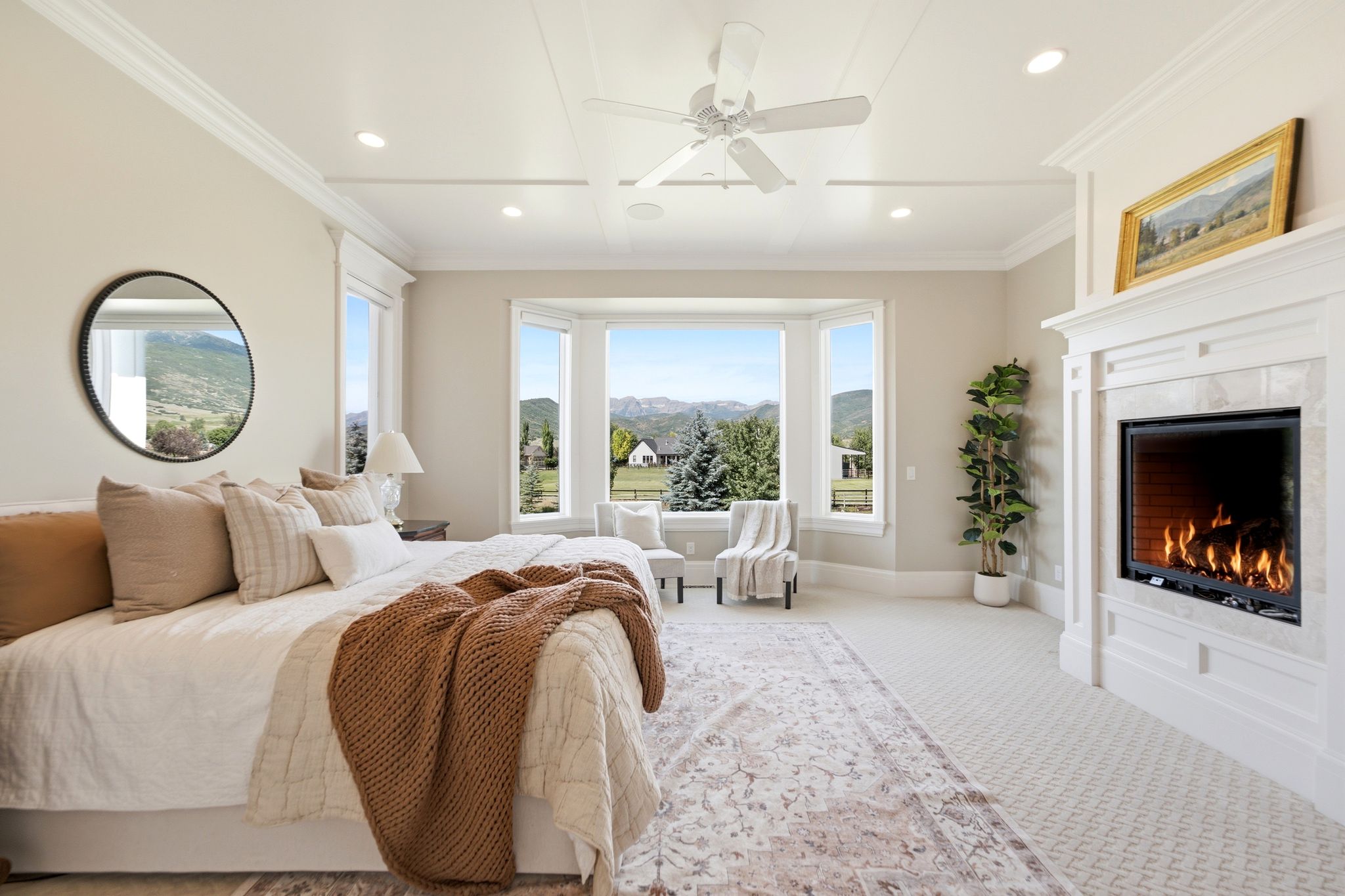 Spacious room featuring a bay window with mountain and tree scenery, a recessed fireplace with a white mantel, and crown molding