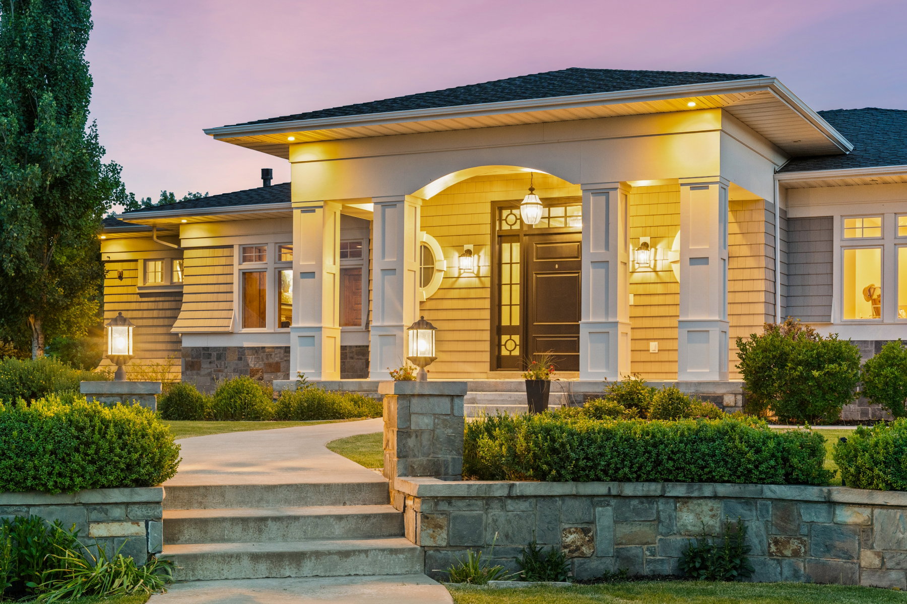 Inviting stone and concrete pathway leading to a covered entry with white columns and a dark paneled front door