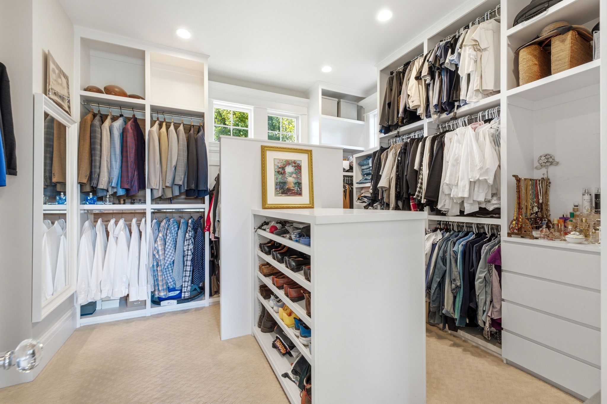 Custom closet system featuring extensive hanging rods, multiple shelving units, built-in drawers, and a central island with integrated shoe storage