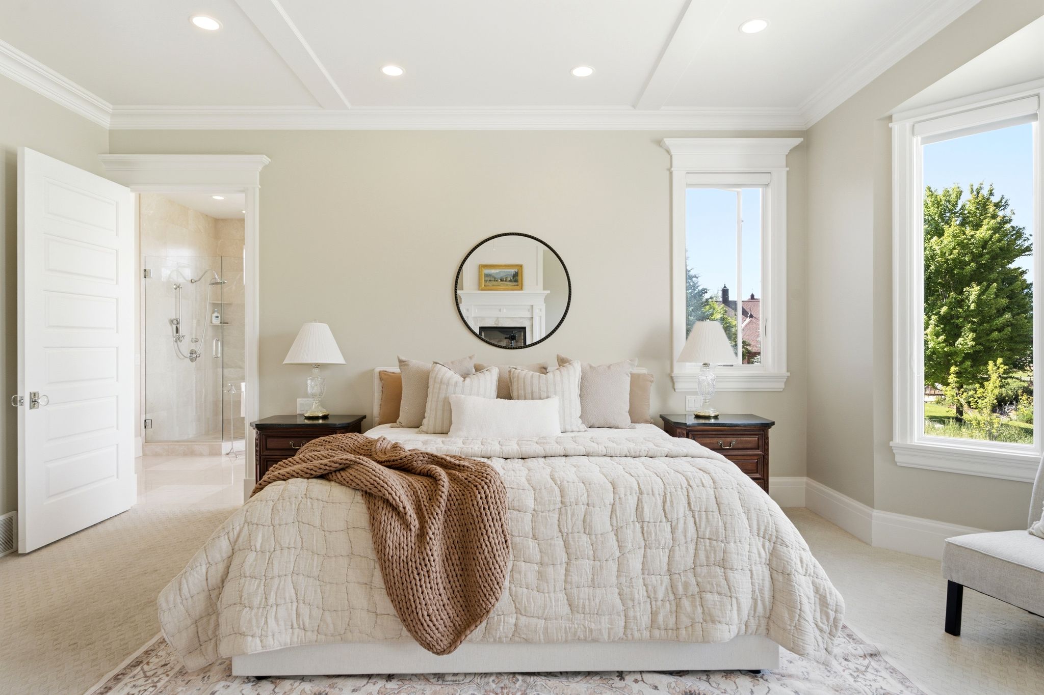 Recessed ceiling lighting with tray ceiling detail, large windows with white trim, and a clear glass shower enclosure