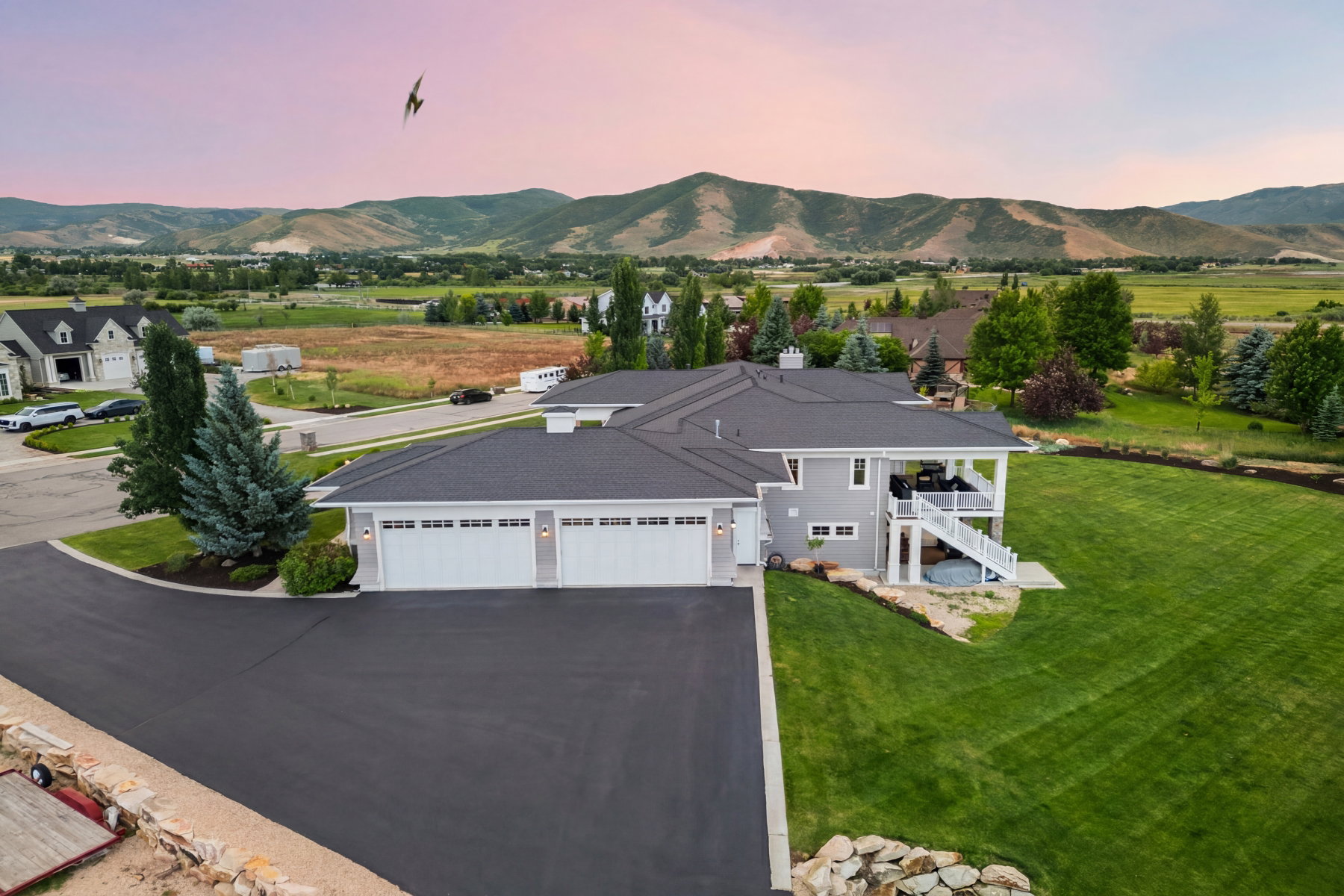 Expansive property featuring a grey exterior with white trim, a multi-car garage, and a covered upper-level deck
