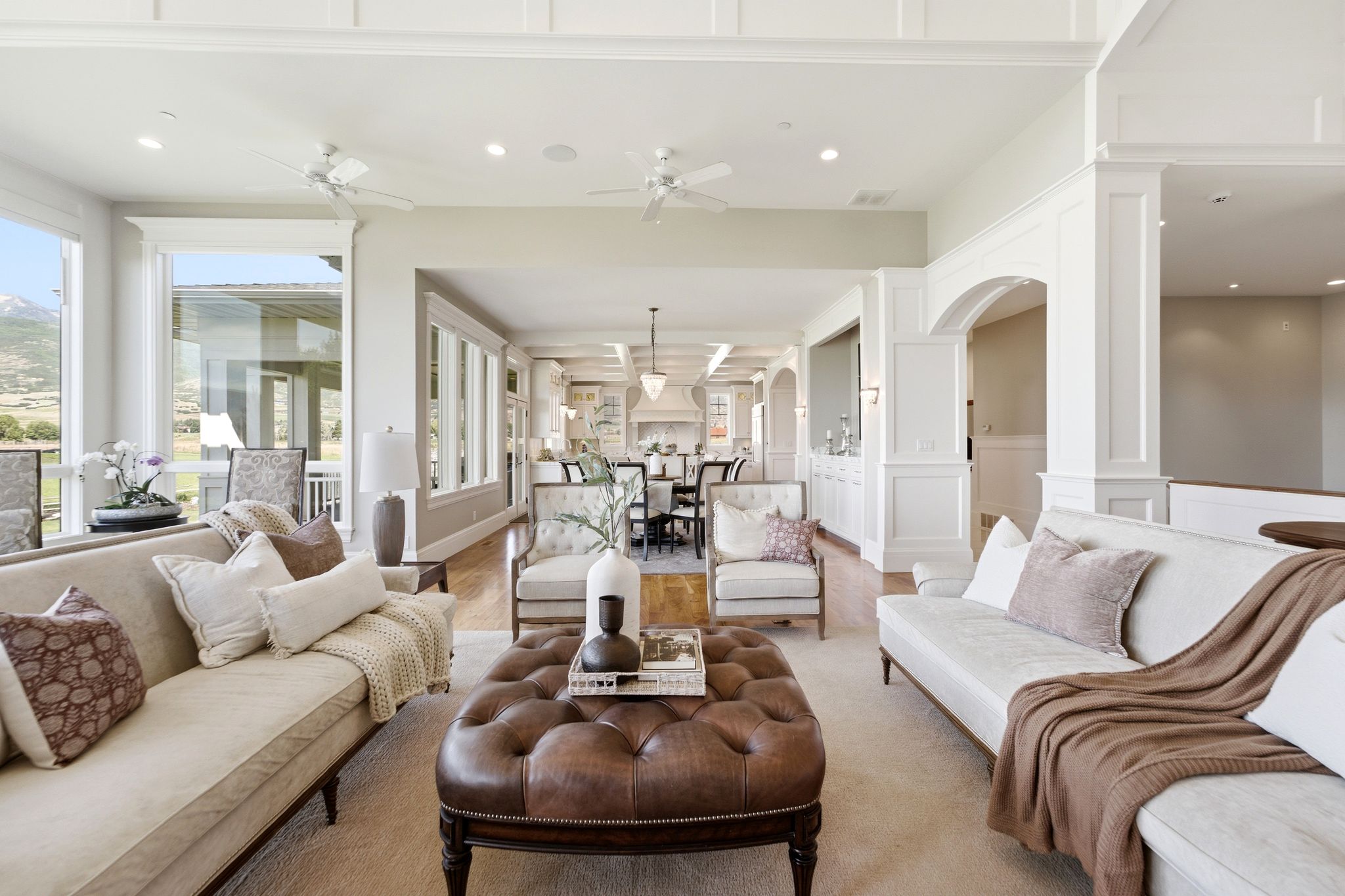 Spacious living area featuring large windows, tray ceilings with recessed lighting, and wood-finish flooring