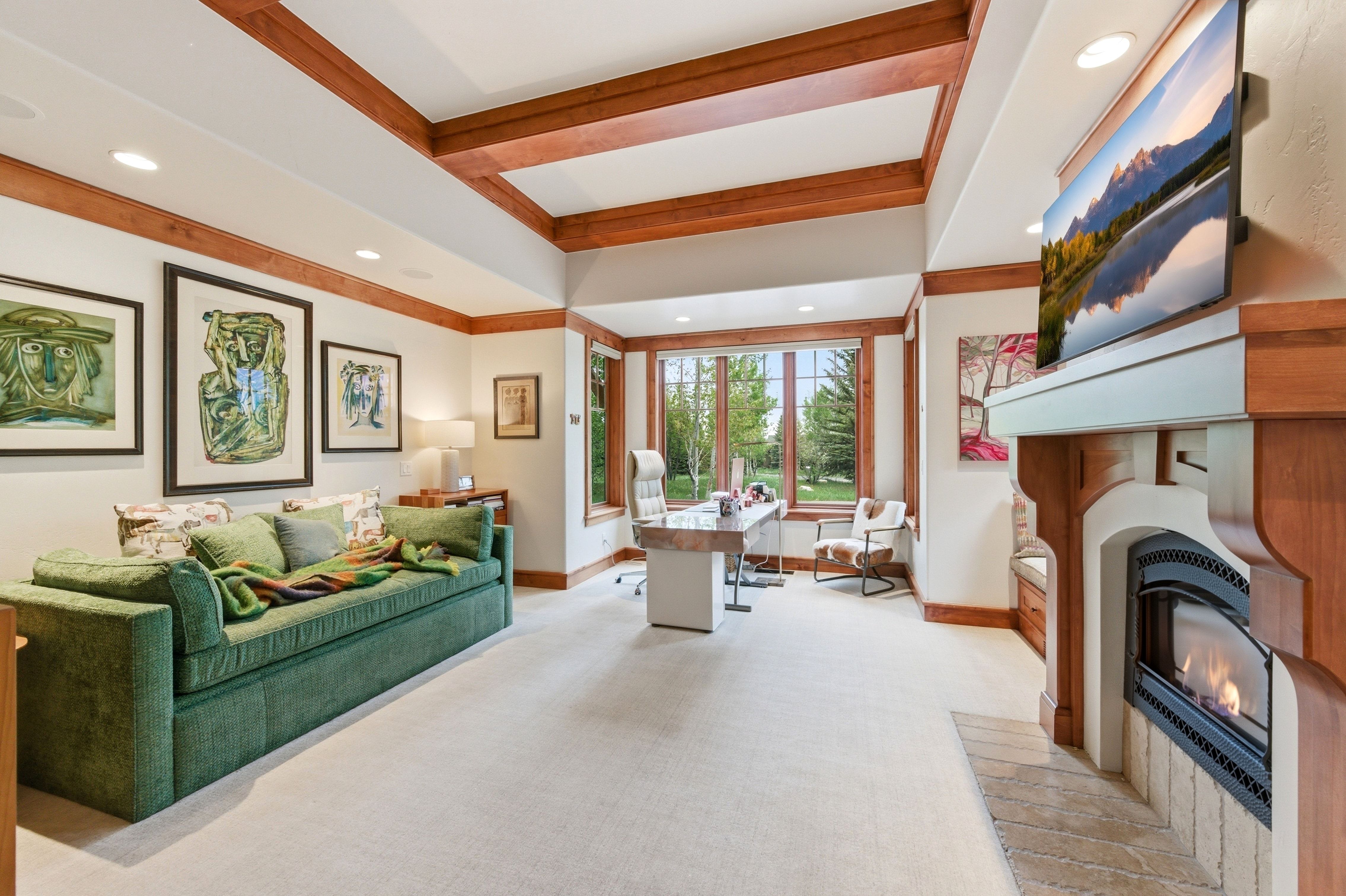 Beamed ceiling design with recessed lighting, stone fireplace, bay window, and light carpet flooring