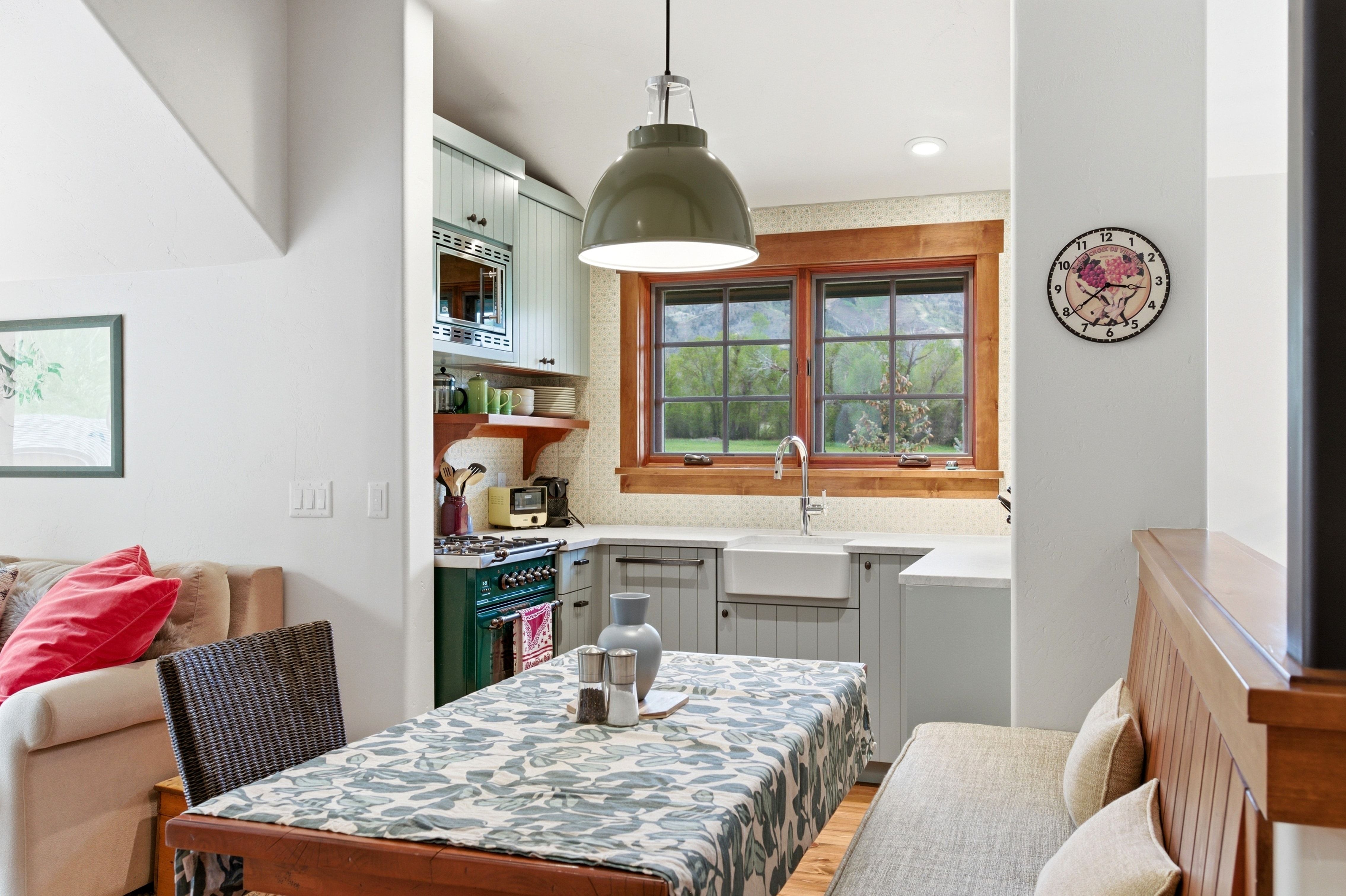 Kitchen area featuring a farmhouse sink, wood-trimmed windows, light blue cabinetry with beadboard detailing, and a built-in bench seating area