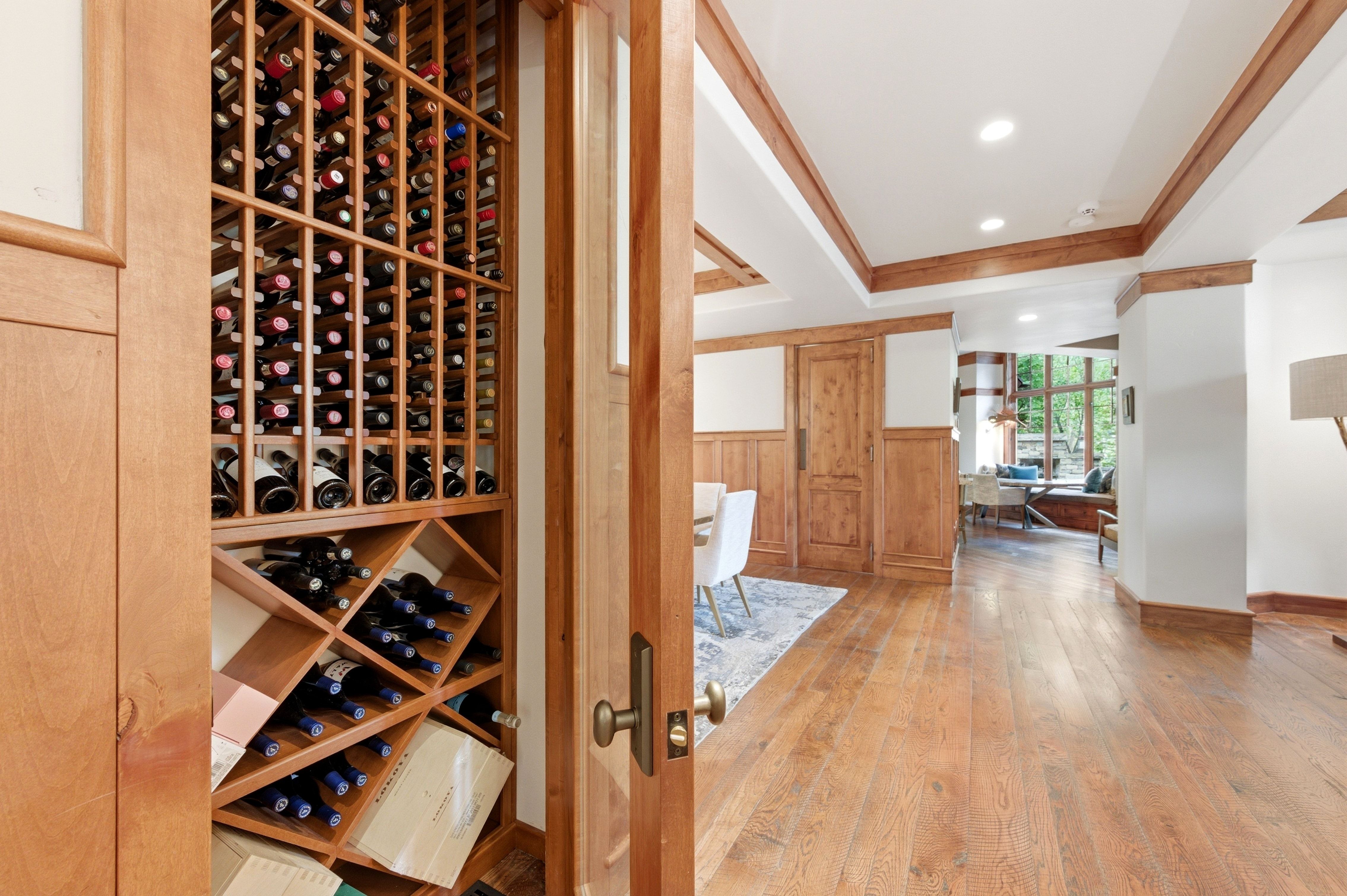 Built-in wood-finish wine storage, wood-finish flooring, recessed lighting, wood-paneled walls, and exposed wood ceiling beams