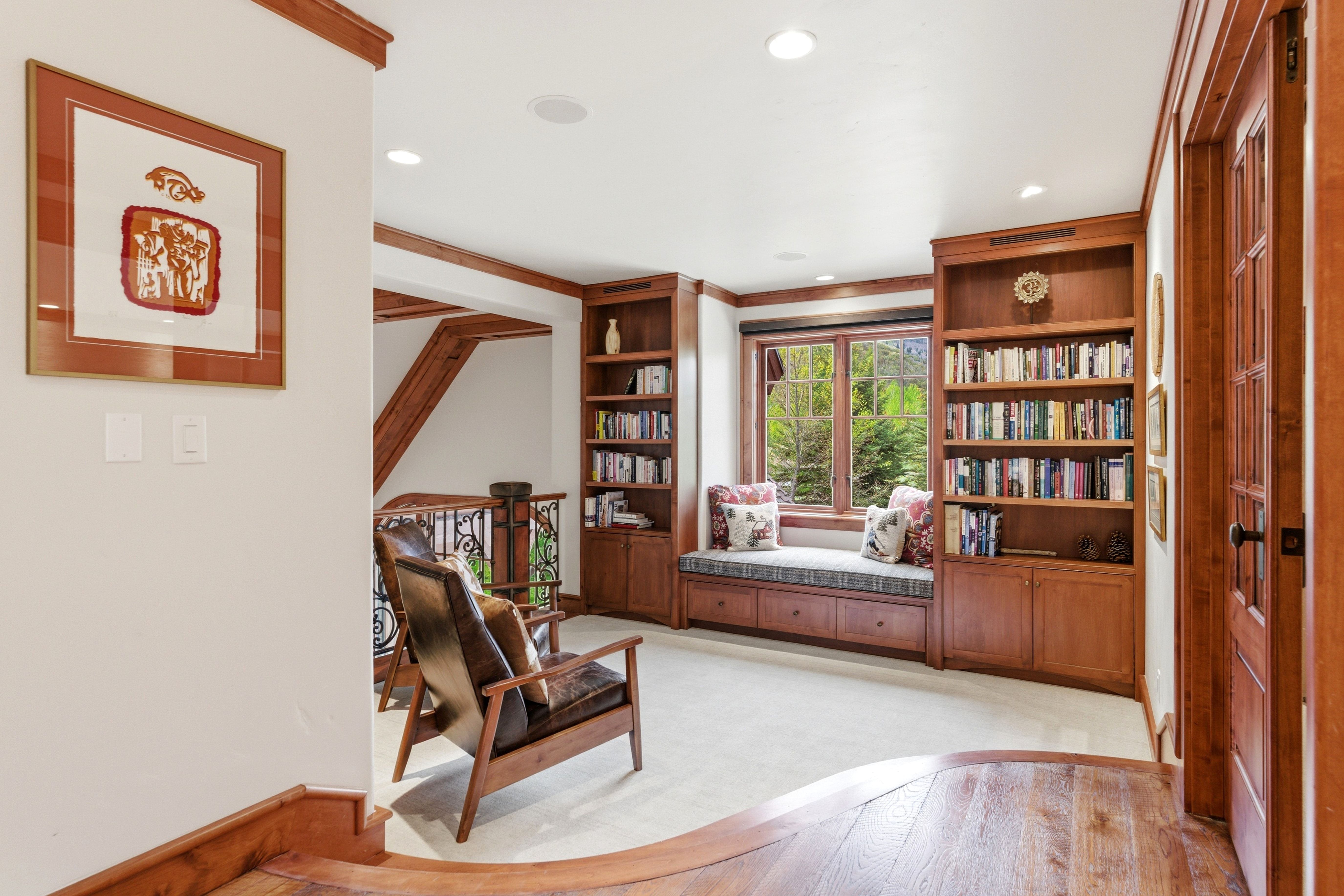 Reading nook featuring a built-in window seat with storage, integrated custom shelving, and a multi-pane window