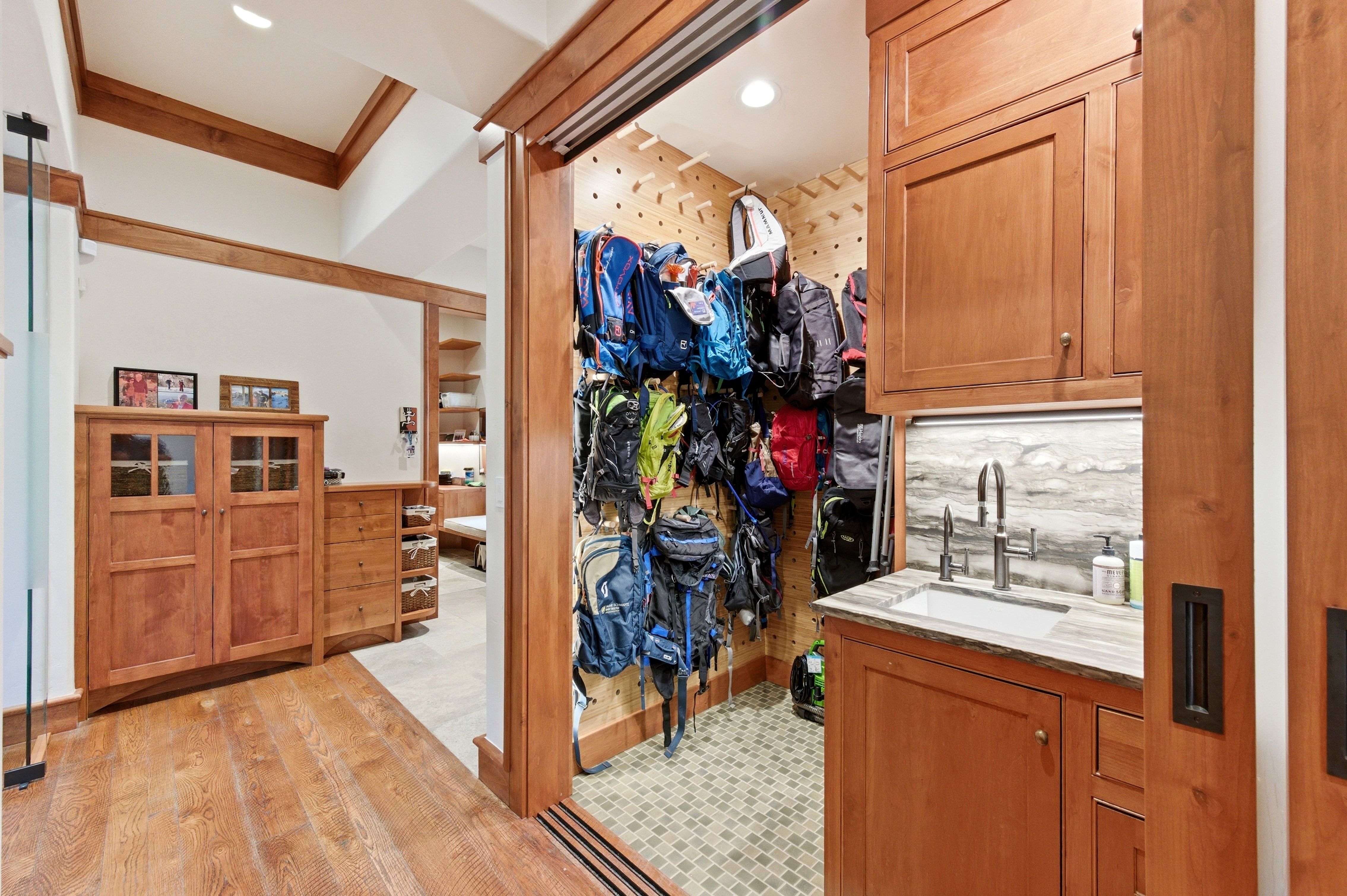 Mudroom featuring wood cabinetry, a built-in sink with a wall-mounted faucet, and a stone-finish countertop