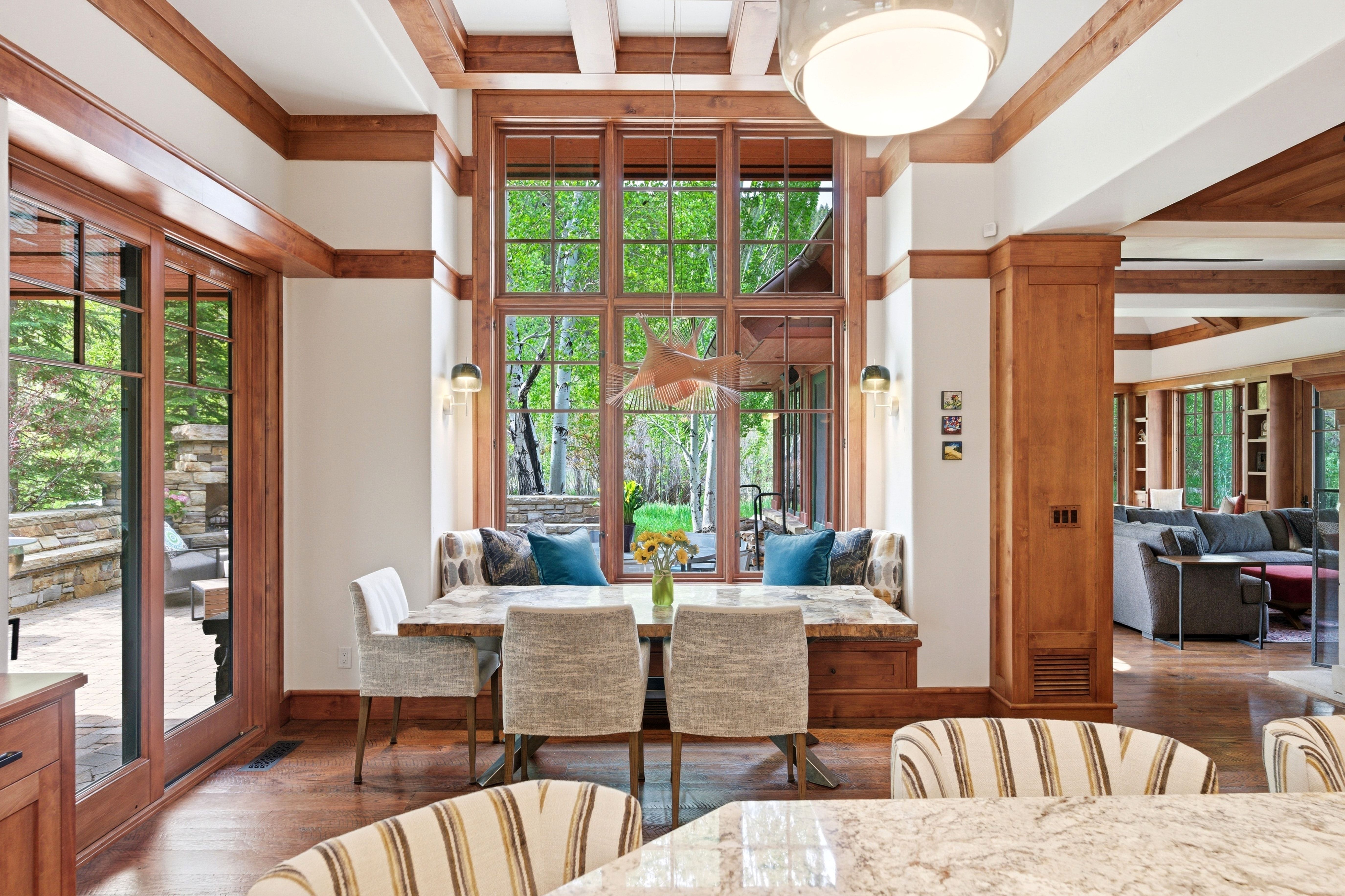 Integrated dining area featuring a built-in window bench, large picture windows, wood-finish flooring, a glass pendant light fixture, and exterior patio access