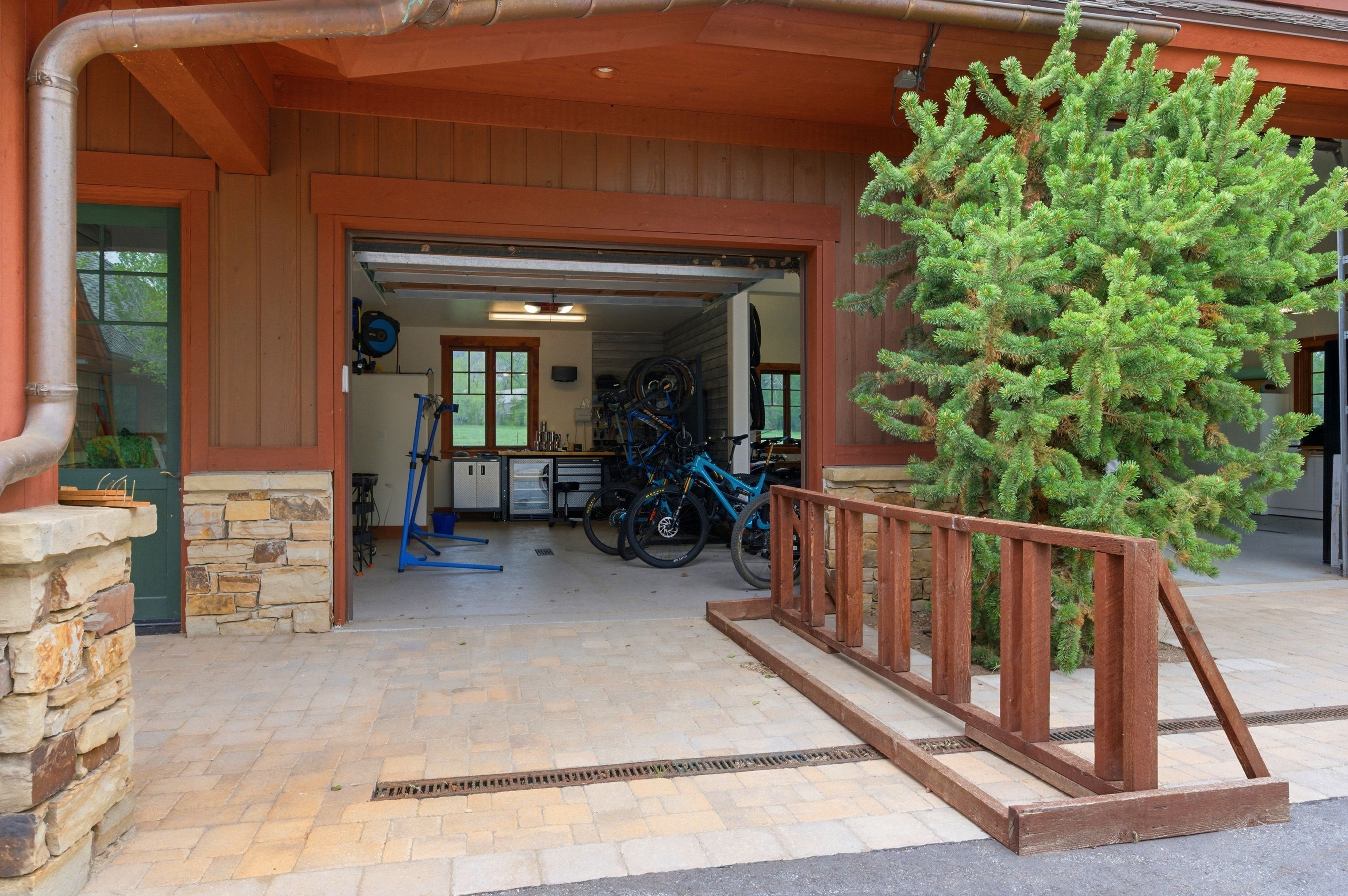 Garage featuring an open bay, stone wainscoting, and wood-paneled walls