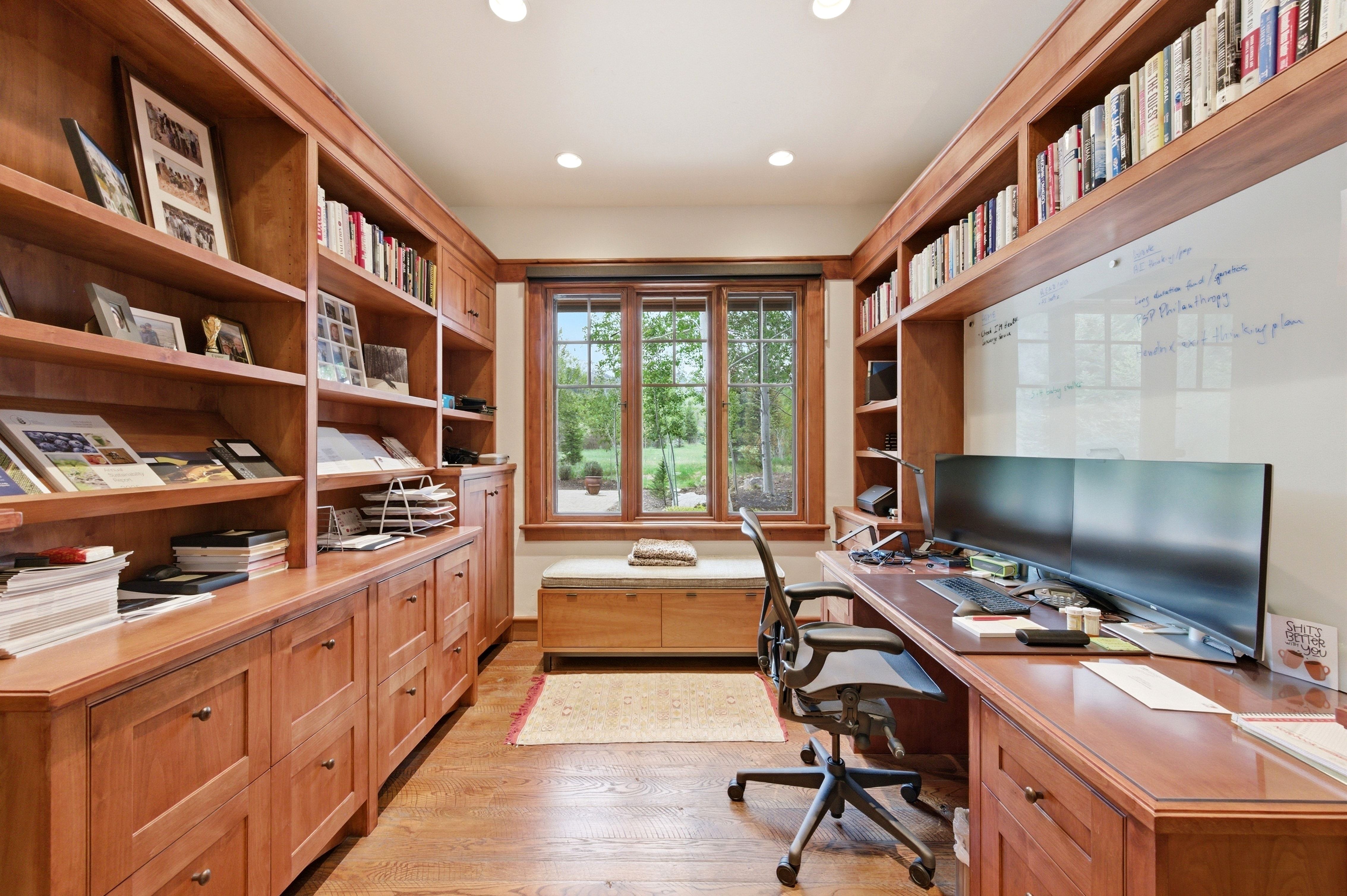 Dedicated office space featuring extensive built-in wooden shelving and cabinetry