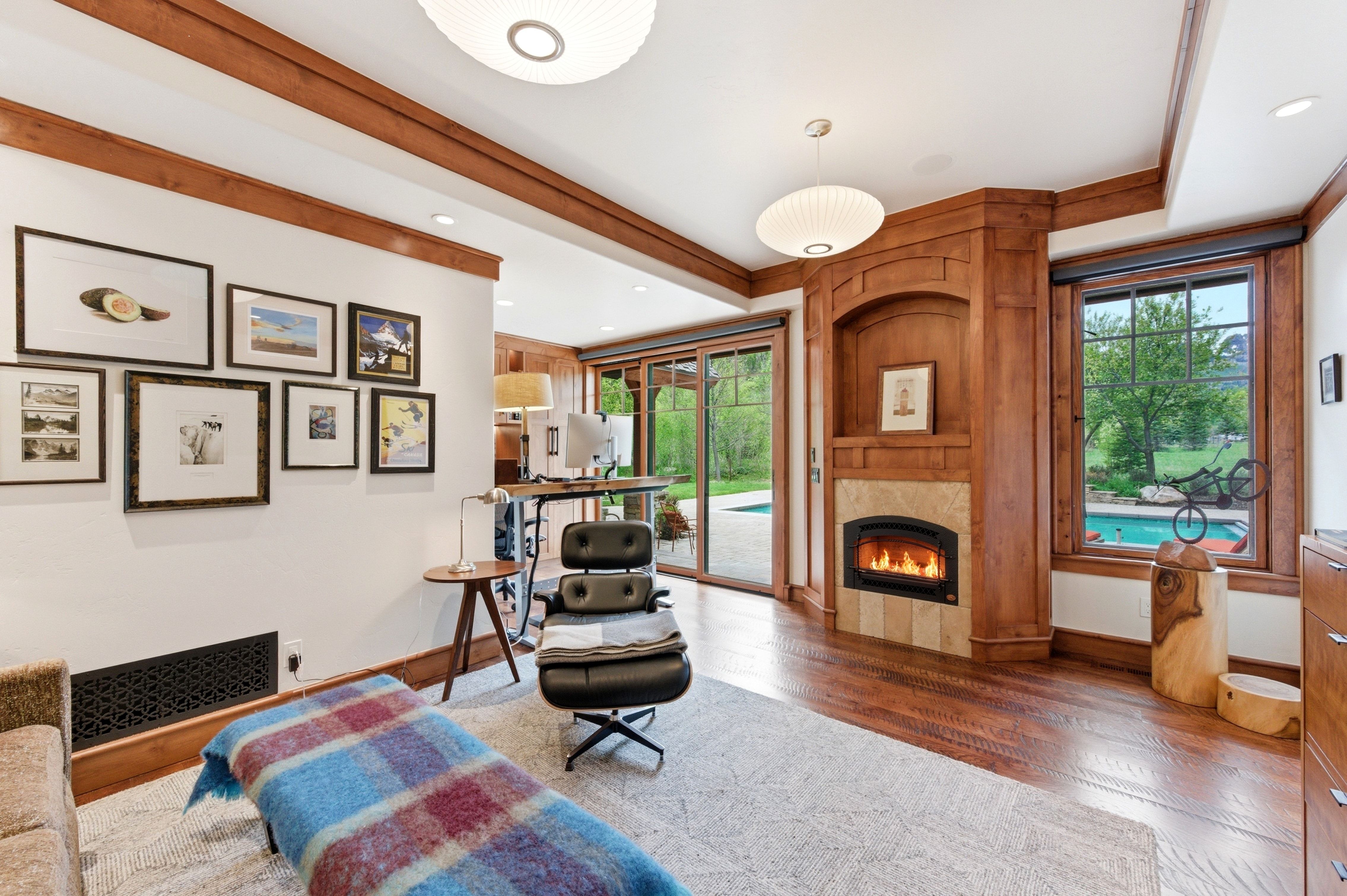 Living area featuring wood-finish flooring, a fireplace with tile surround, and wood-framed windows