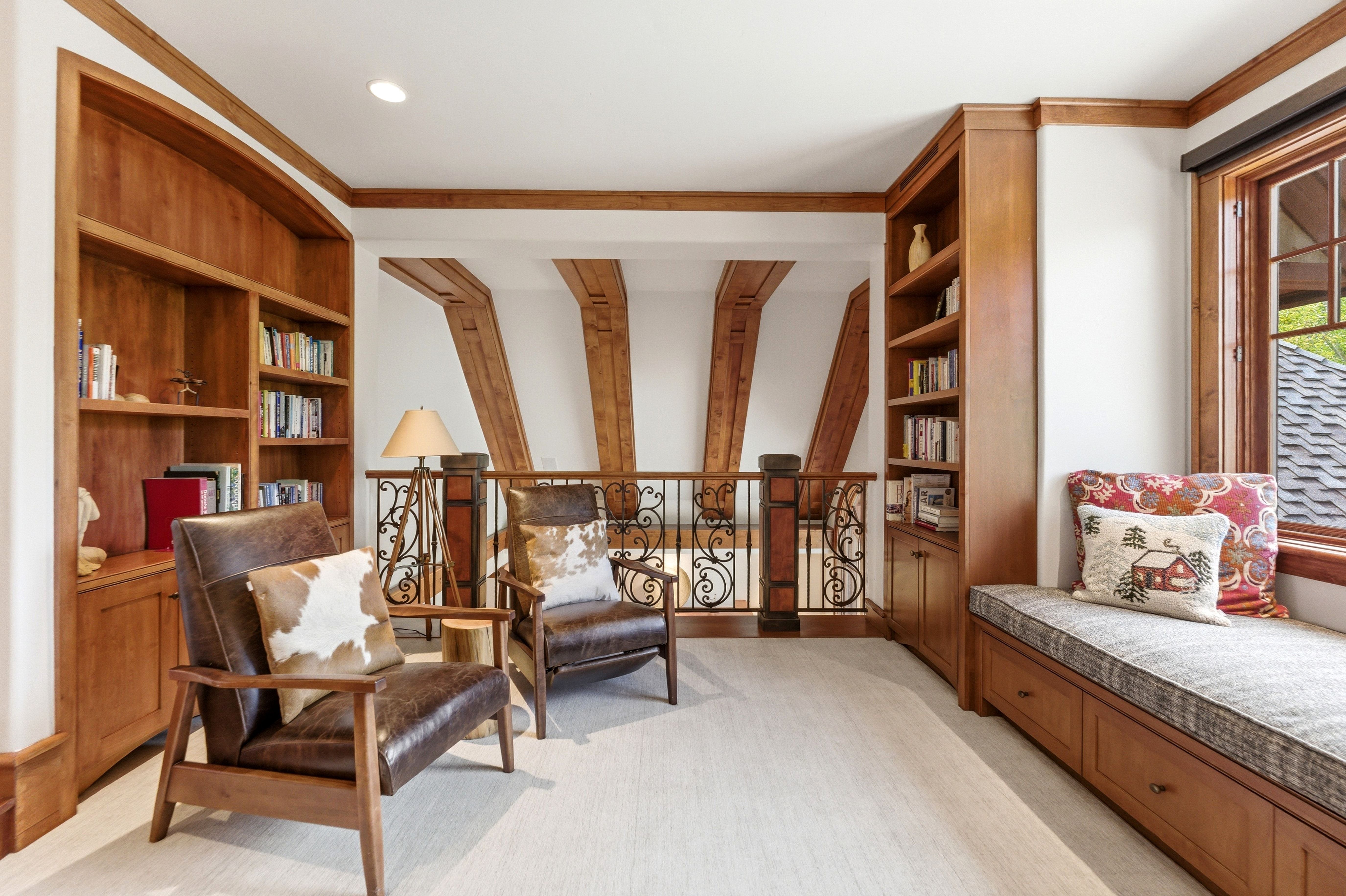 Carpeted landing featuring extensive built-in cabinetry, an integrated window seat with storage drawers, and exposed wood beam accents