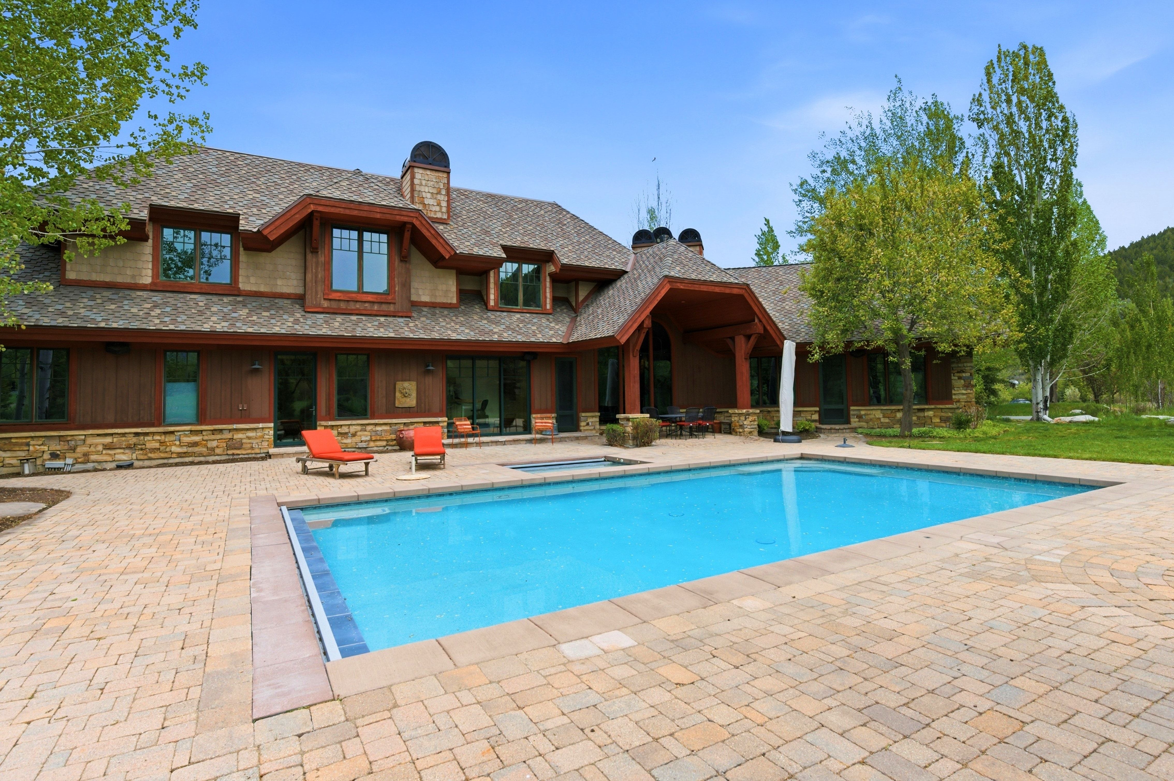 Expansive outdoor space featuring a rectangular swimming pool, integrated spa, and extensive paver patio
