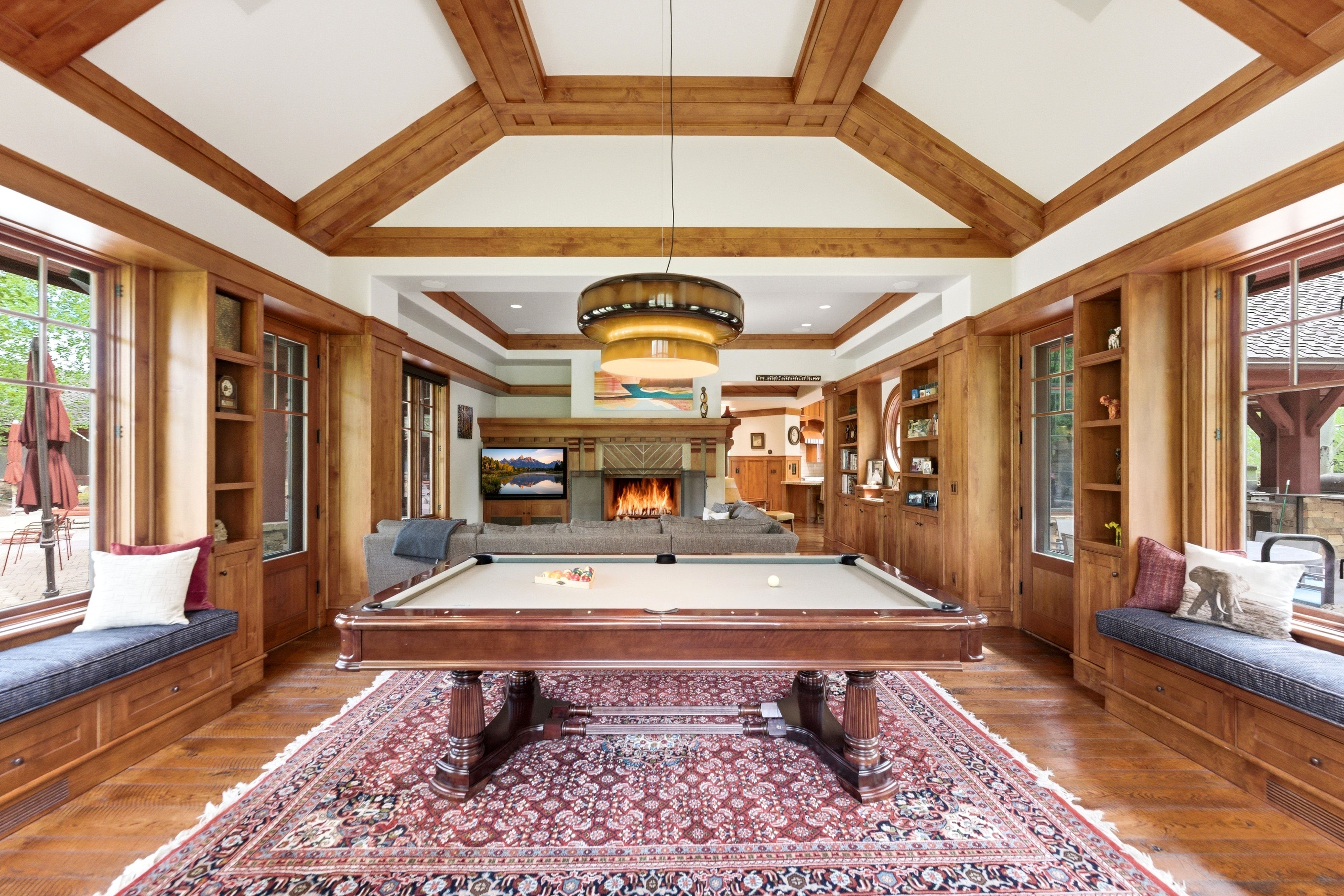 Spacious entertainment area featuring wood-finish flooring and exposed wood ceiling beams