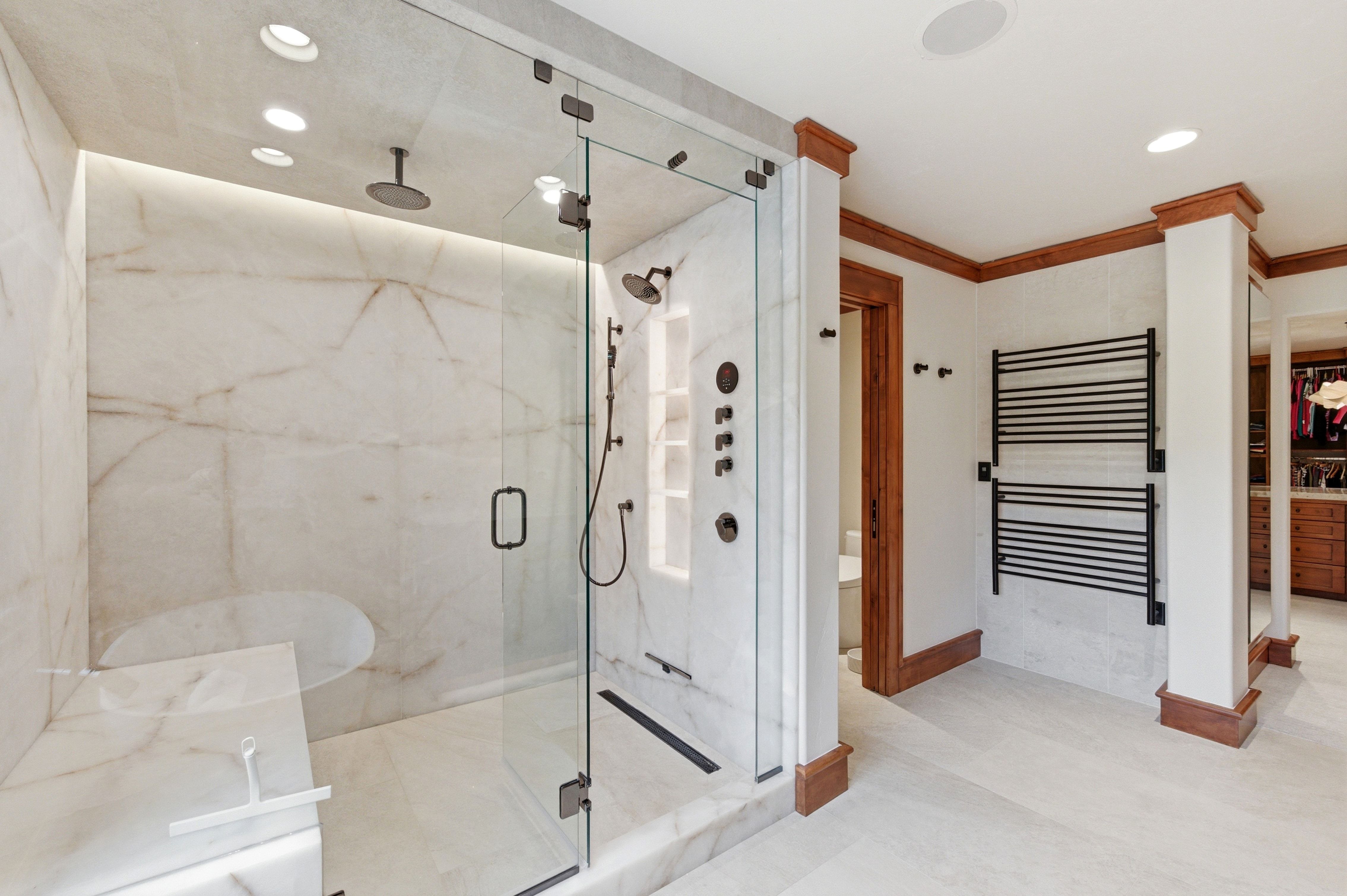 Oversized walk-in shower with full-height stone slab walls, integrated bench, and multiple showerheads