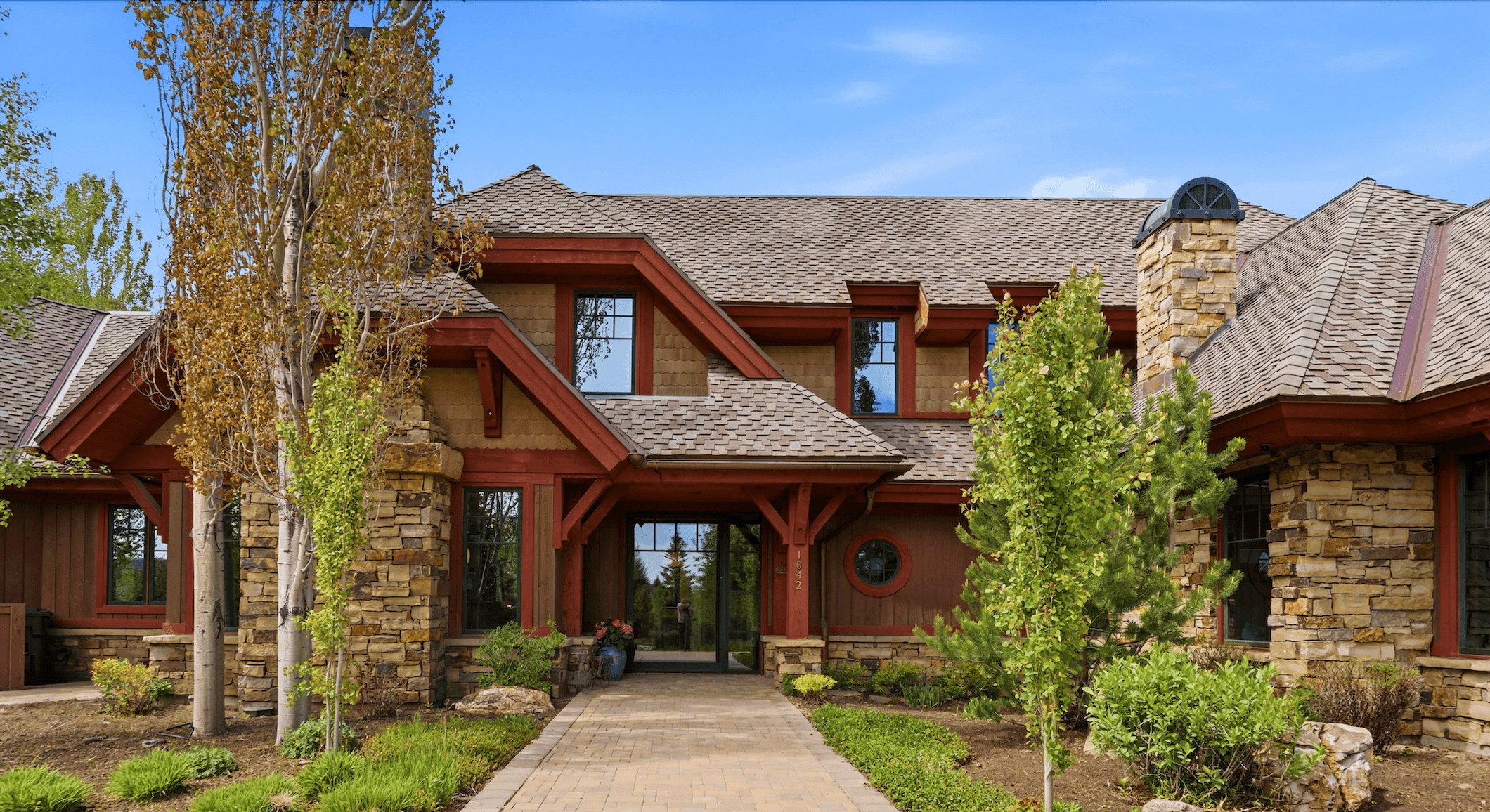 Stone and wood-sided exterior featuring multiple gables, dormer windows, and a prominent stone chimney