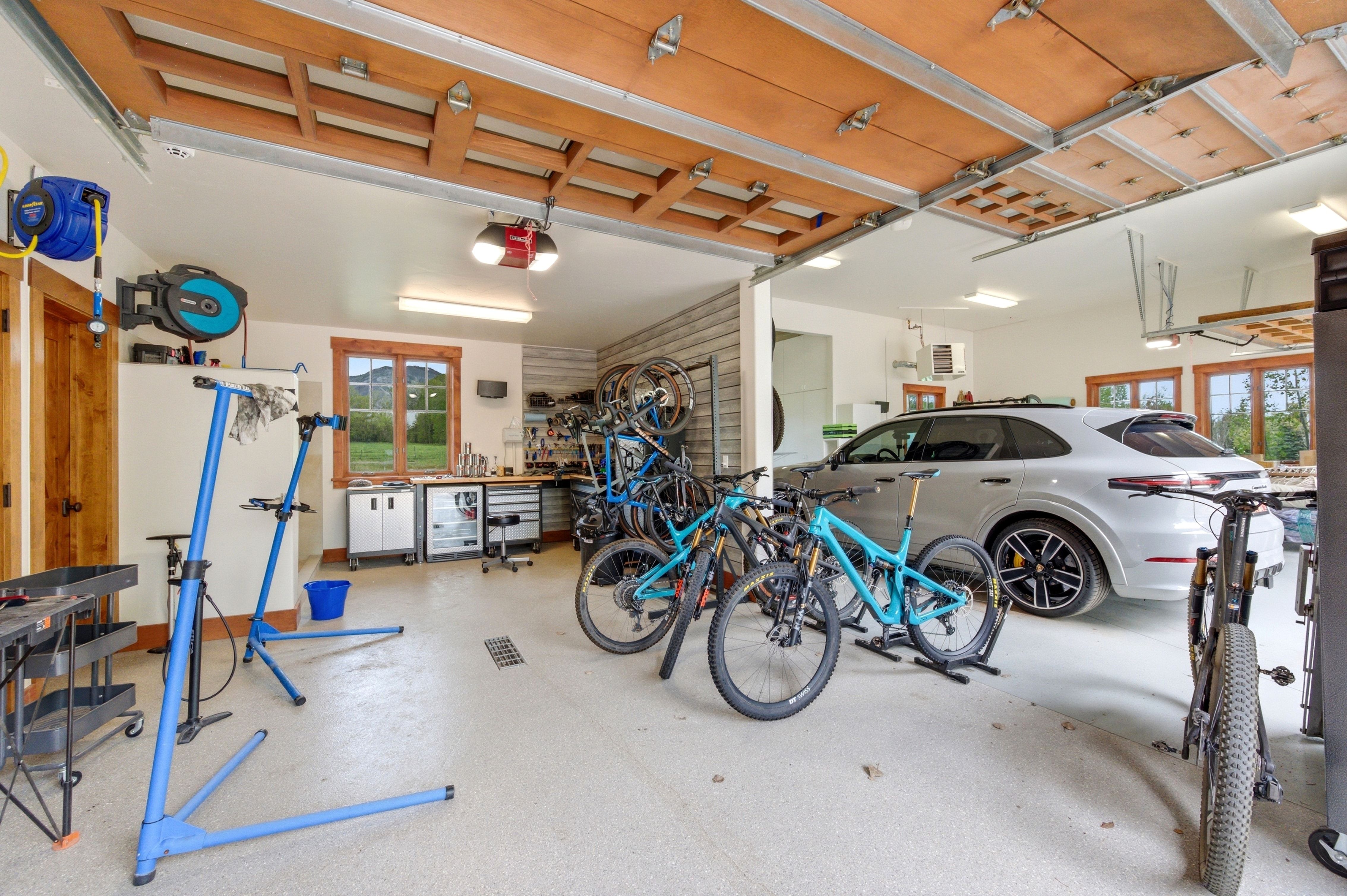 Spacious garage featuring a durable epoxy floor coating, exposed wood ceiling beams, and multiple windows with wood trim