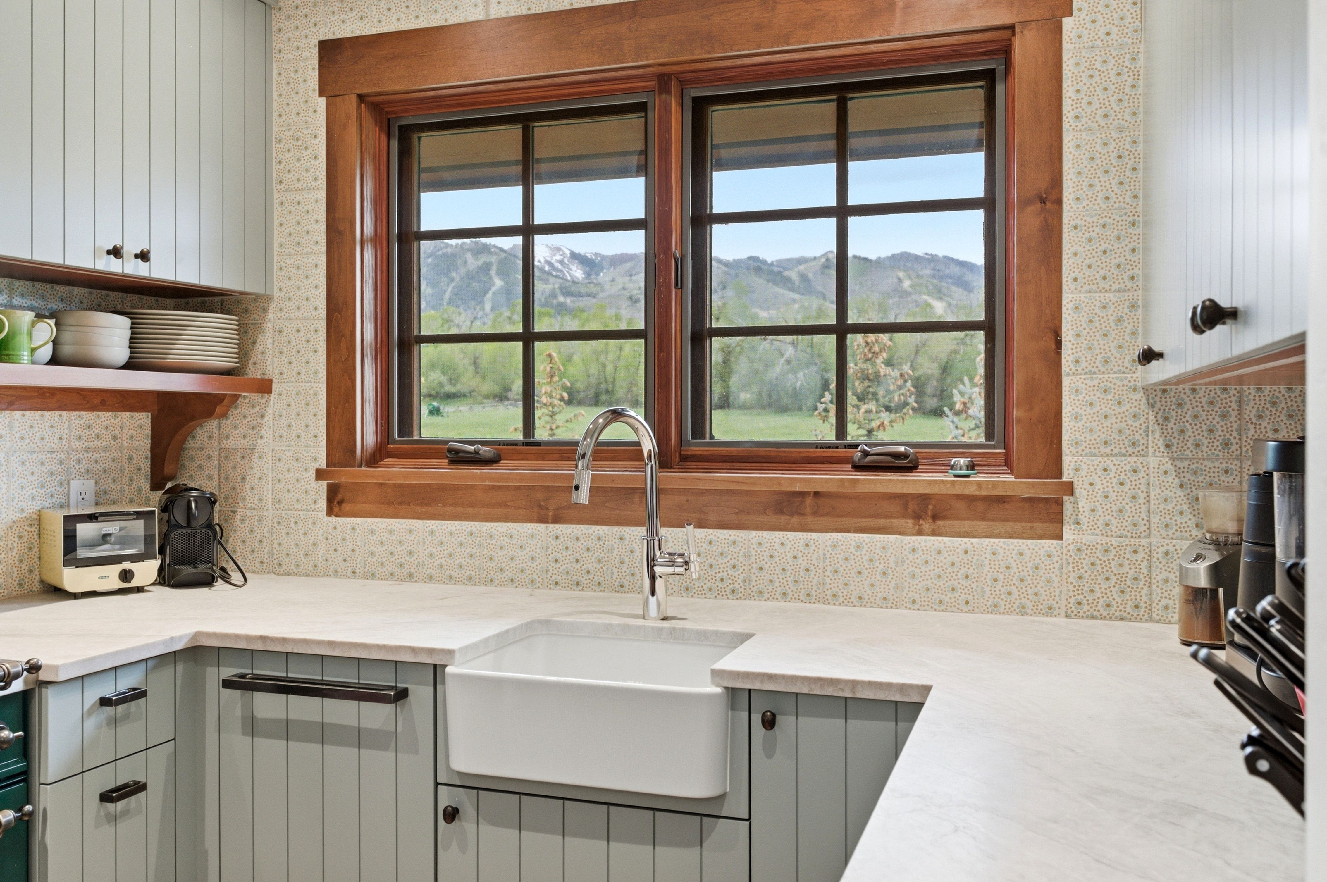 Kitchen window with natural wood trim framing mountain and green landscape scenery