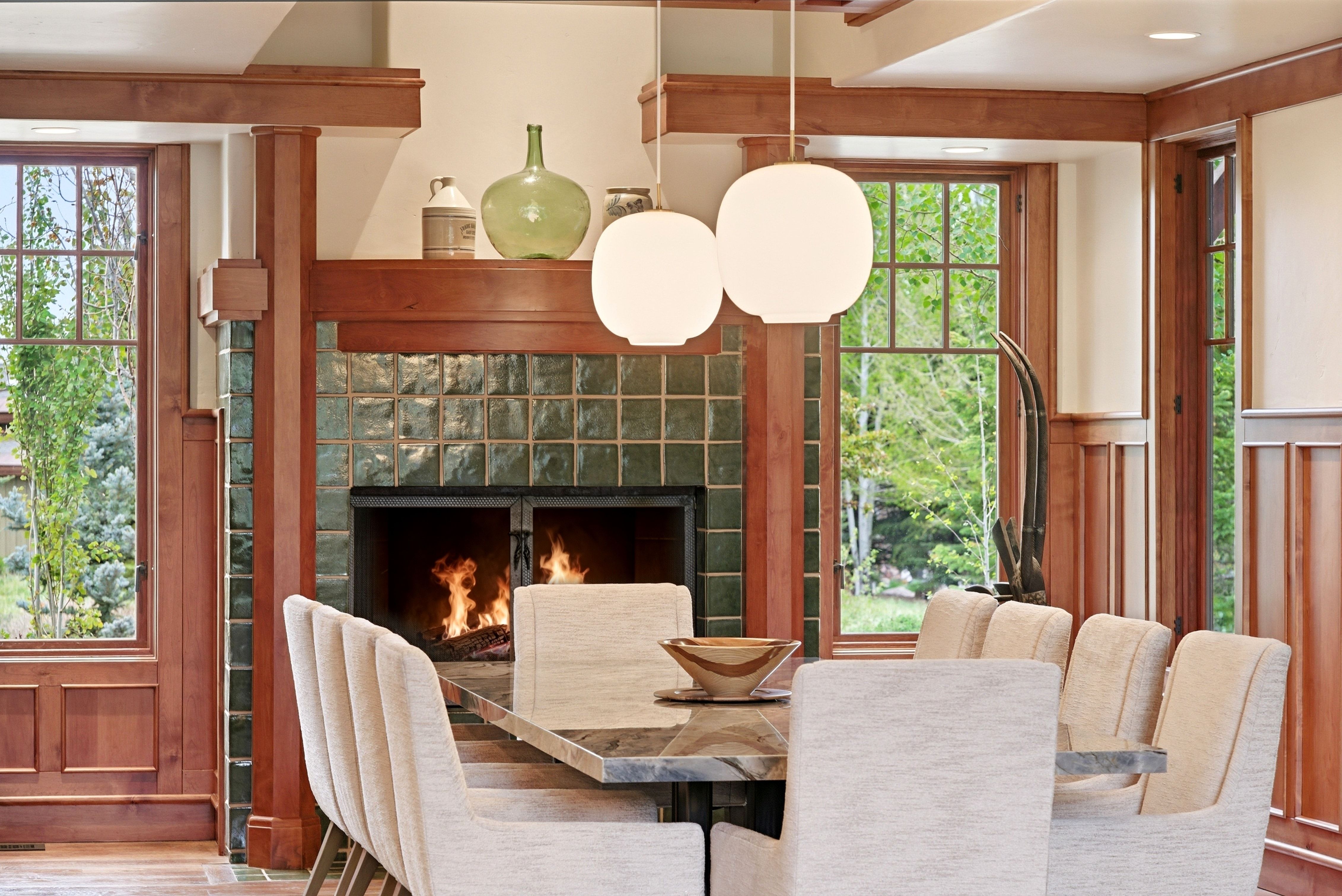 Dining area featuring a tiled fireplace with wood surround, dual globe pendant lights, and a stone-top dining table