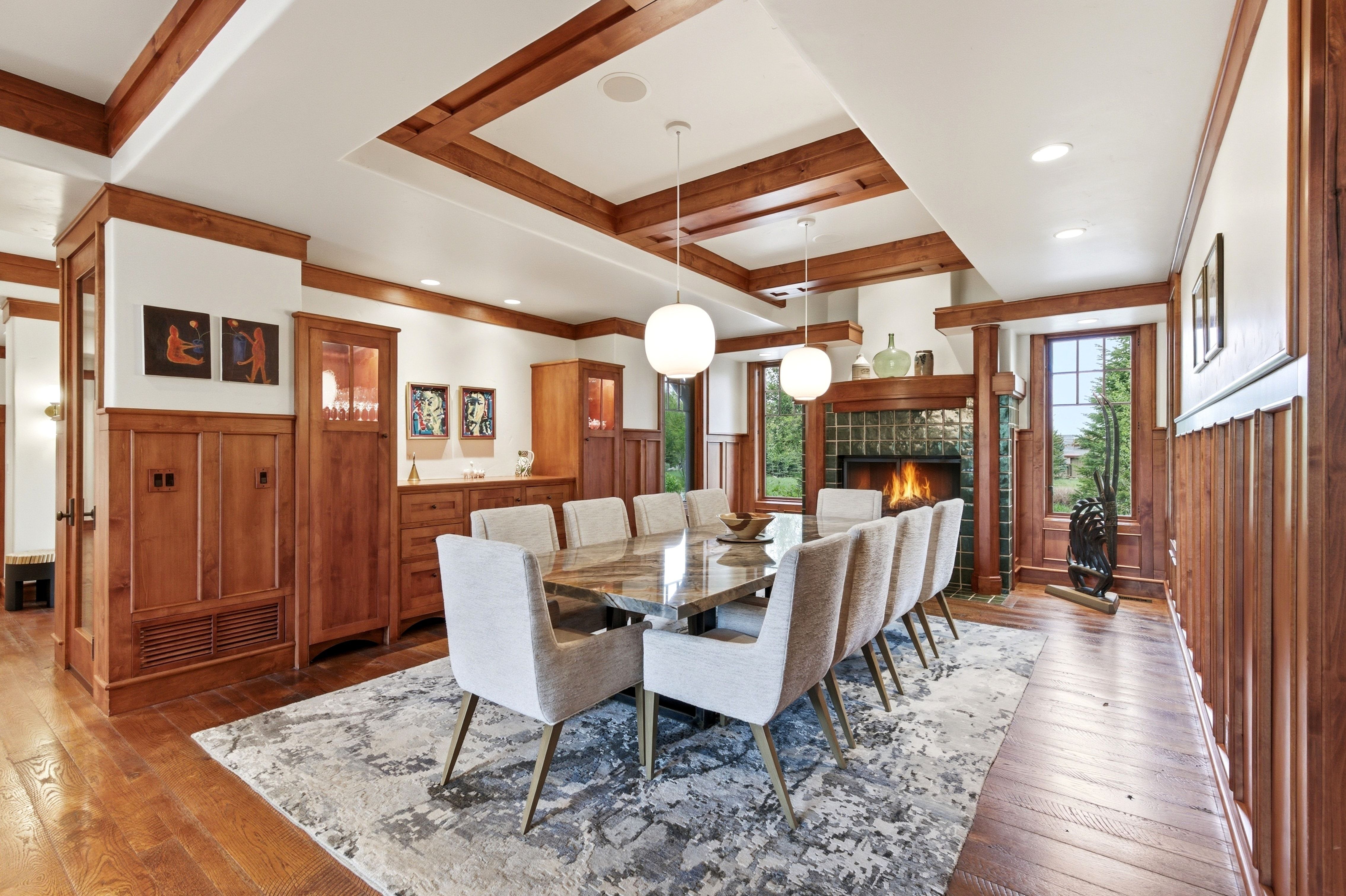 Dining area featuring extensive wood-finish wall paneling and trim, a recessed ceiling with wood beams, and recessed lighting