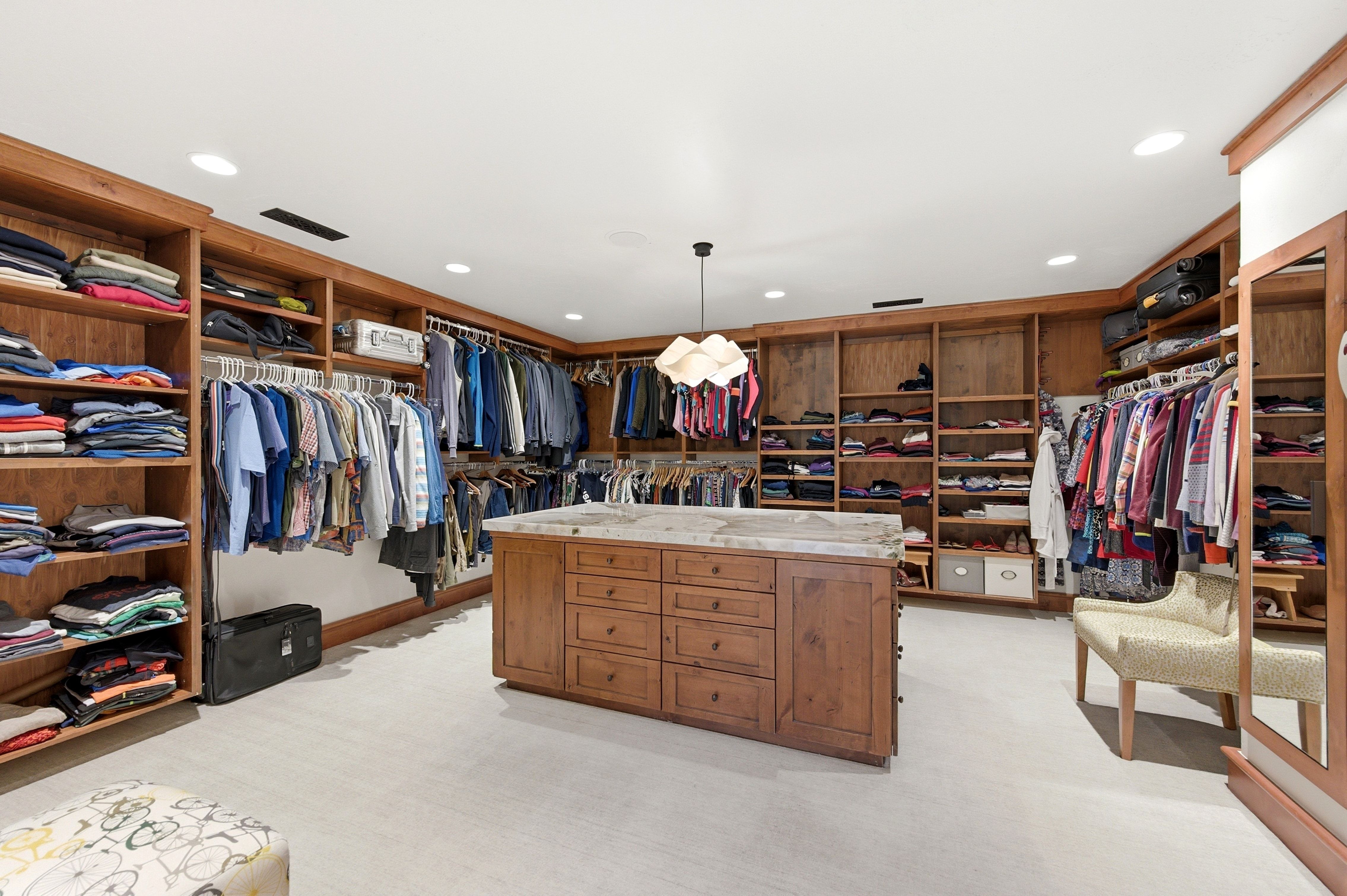 Walk-in closet featuring extensive built-in wooden shelving, multiple hanging rods, and recessed lighting