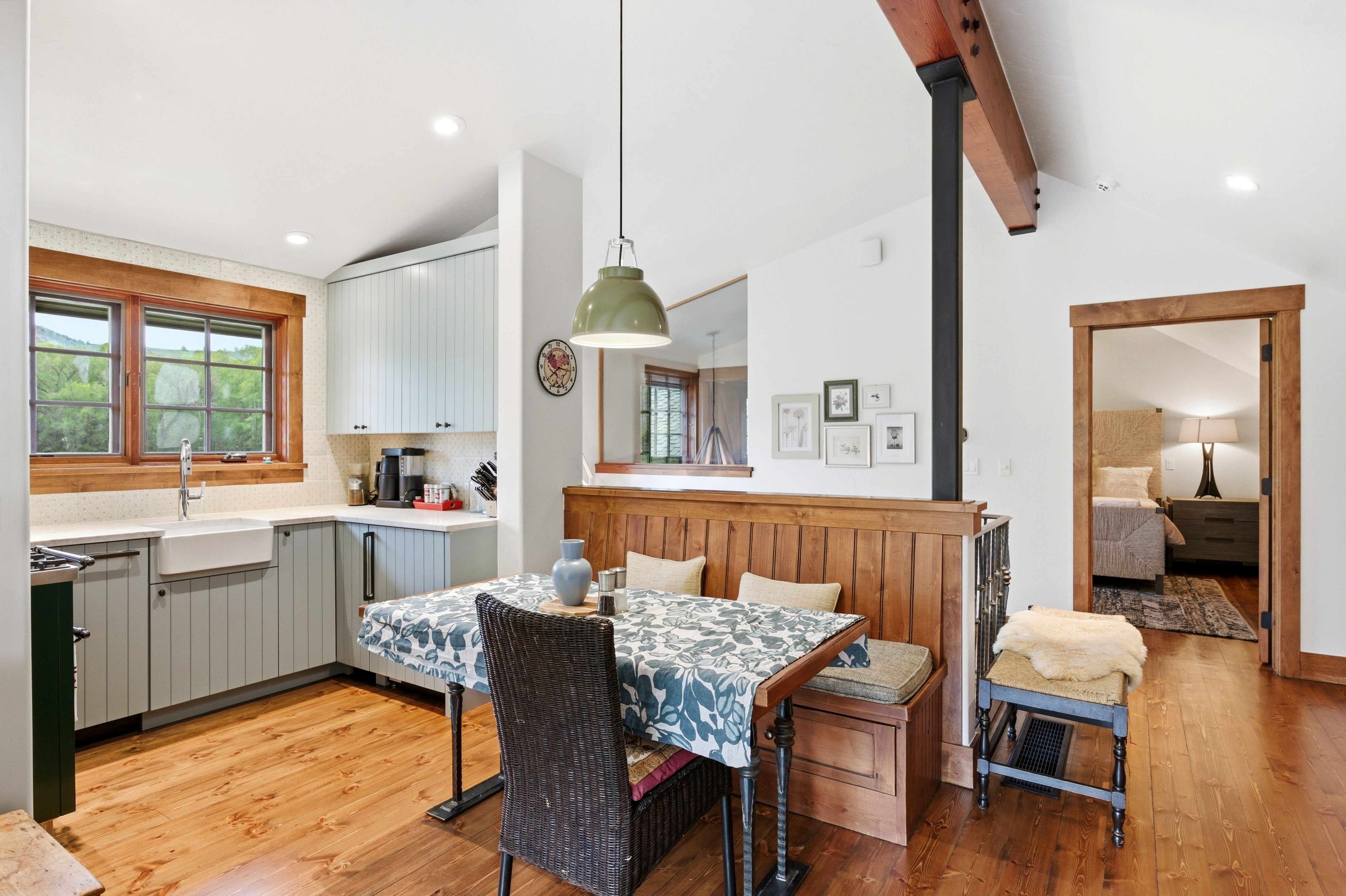 Open-concept kitchen and dining area featuring wood-finish flooring, light gray cabinetry, and a farmhouse sink