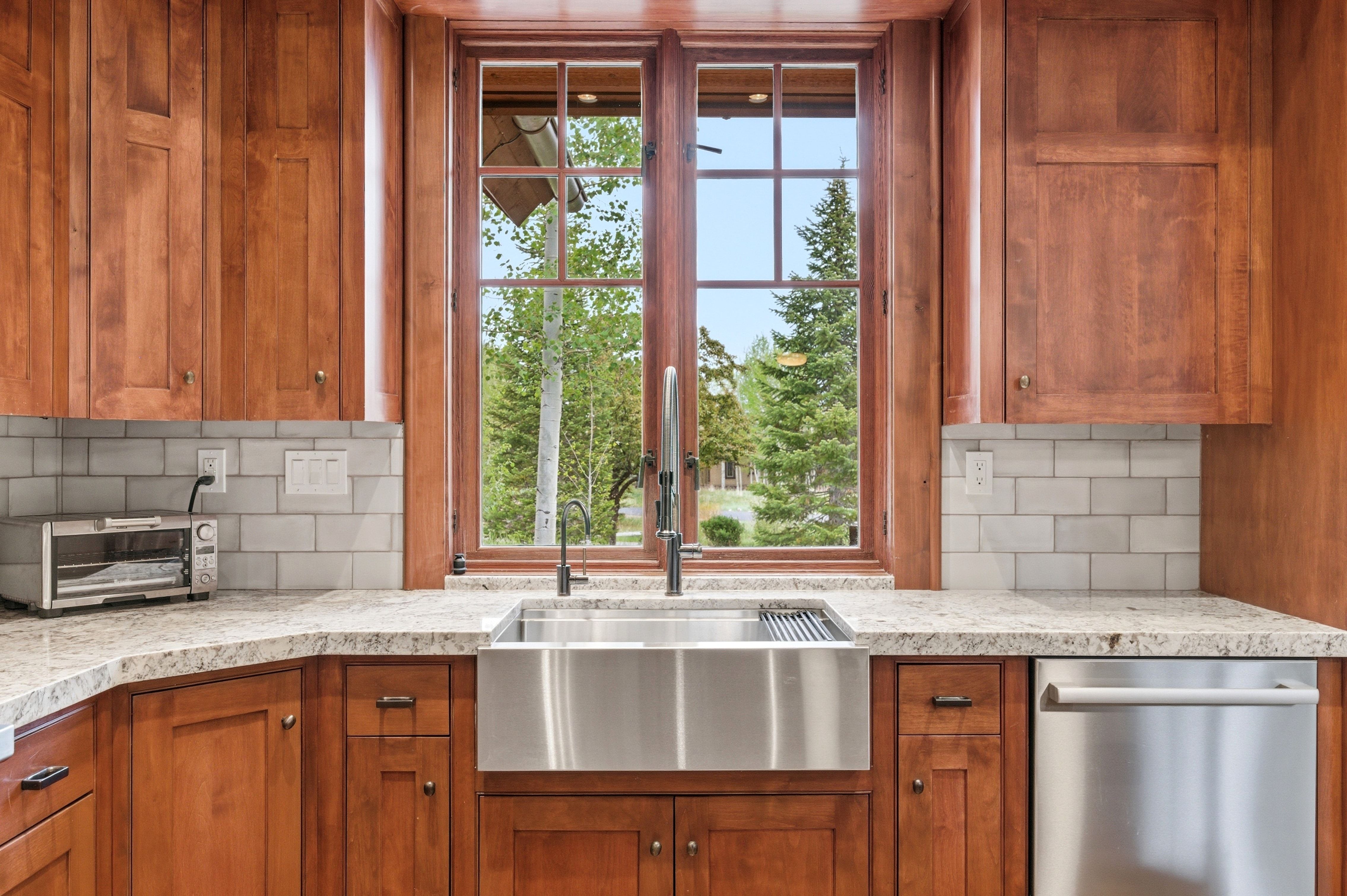 Kitchen featuring a stainless steel farmhouse sink, granite countertops, and a subway tile backsplash