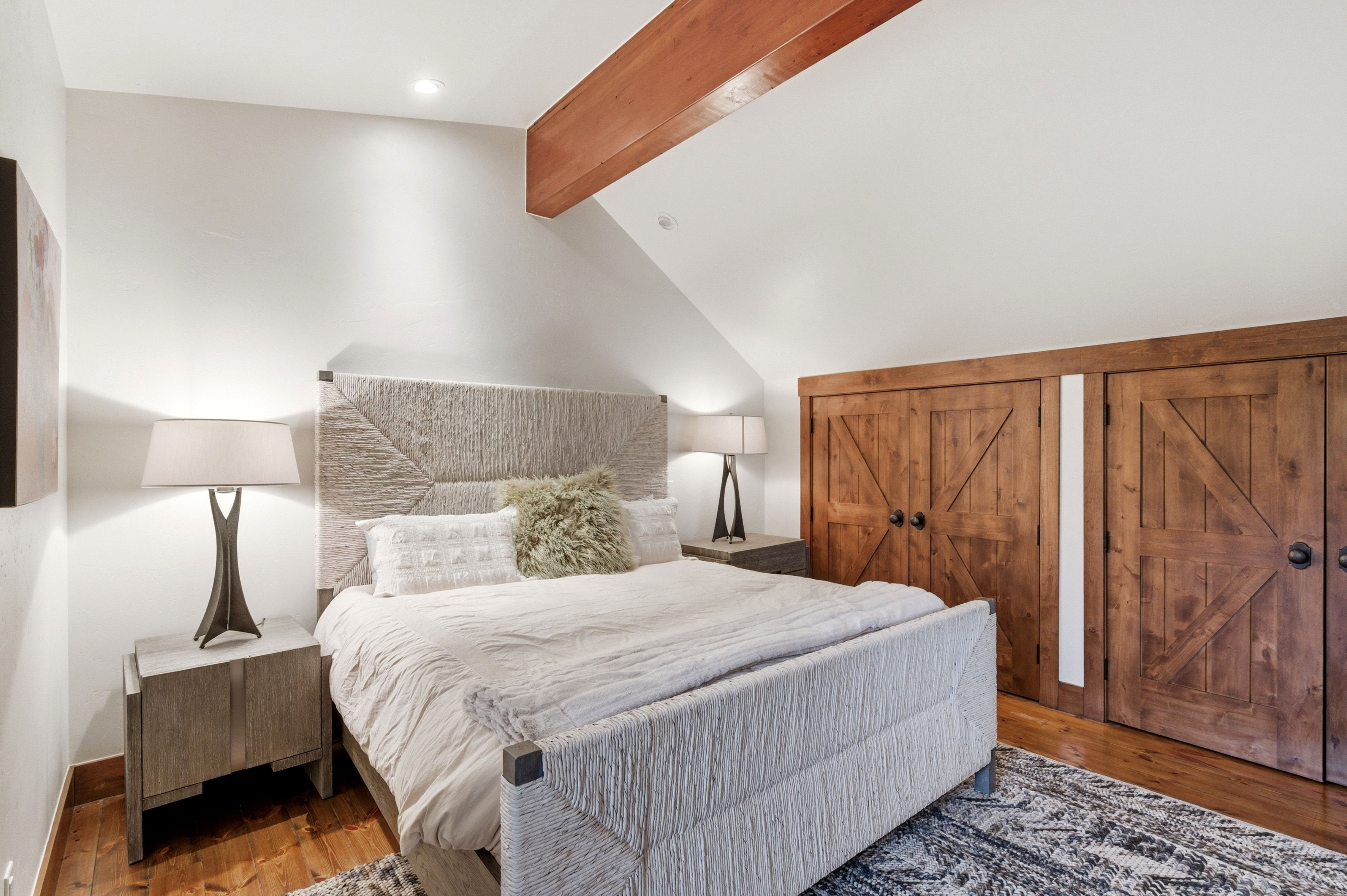 Wood-finish flooring paired with white walls, featuring a prominent wood beam and built-in wood-paneled closet doors