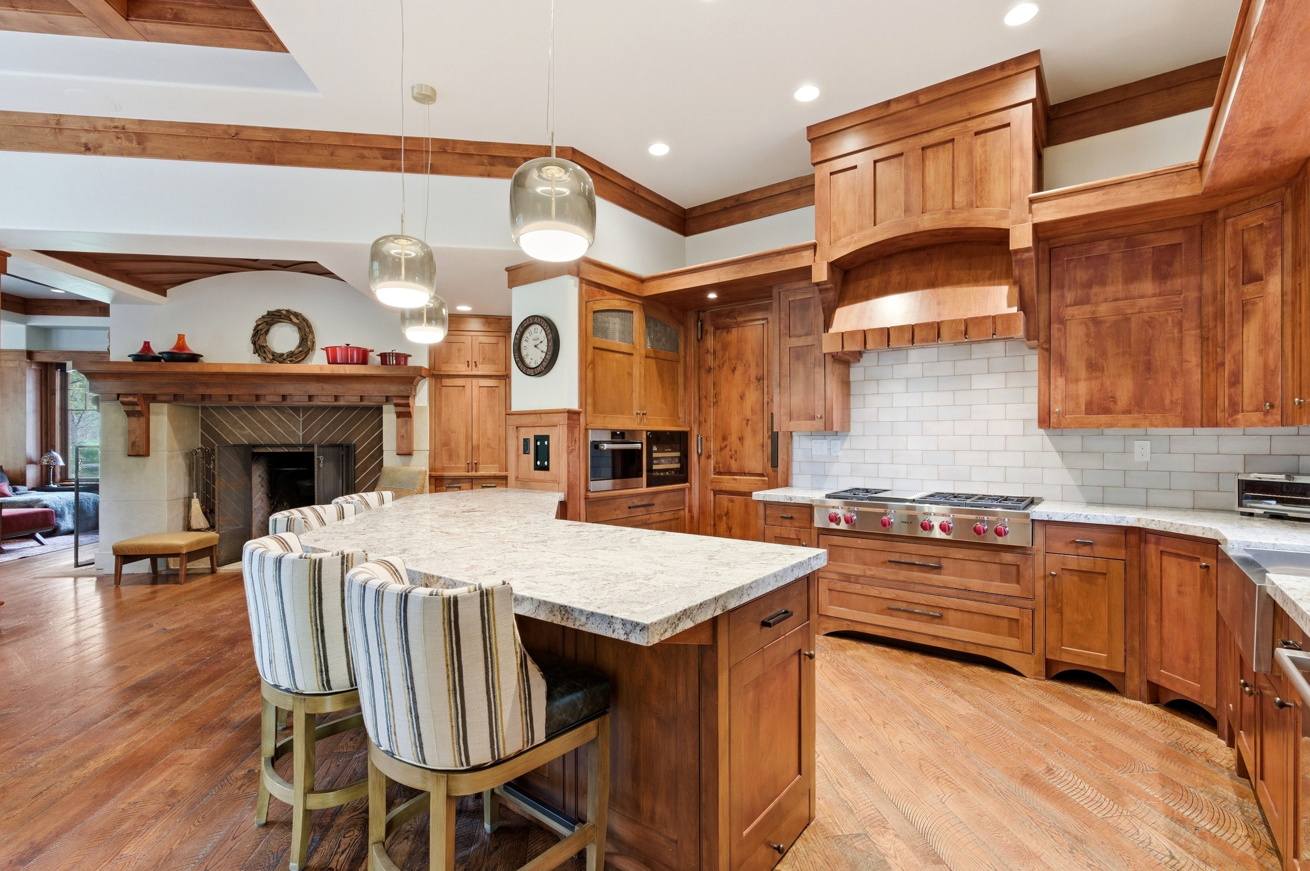 Gourmet kitchen featuring a large stone countertop island, custom wood cabinetry, stainless steel range with a tile backsplash, and recessed lighting