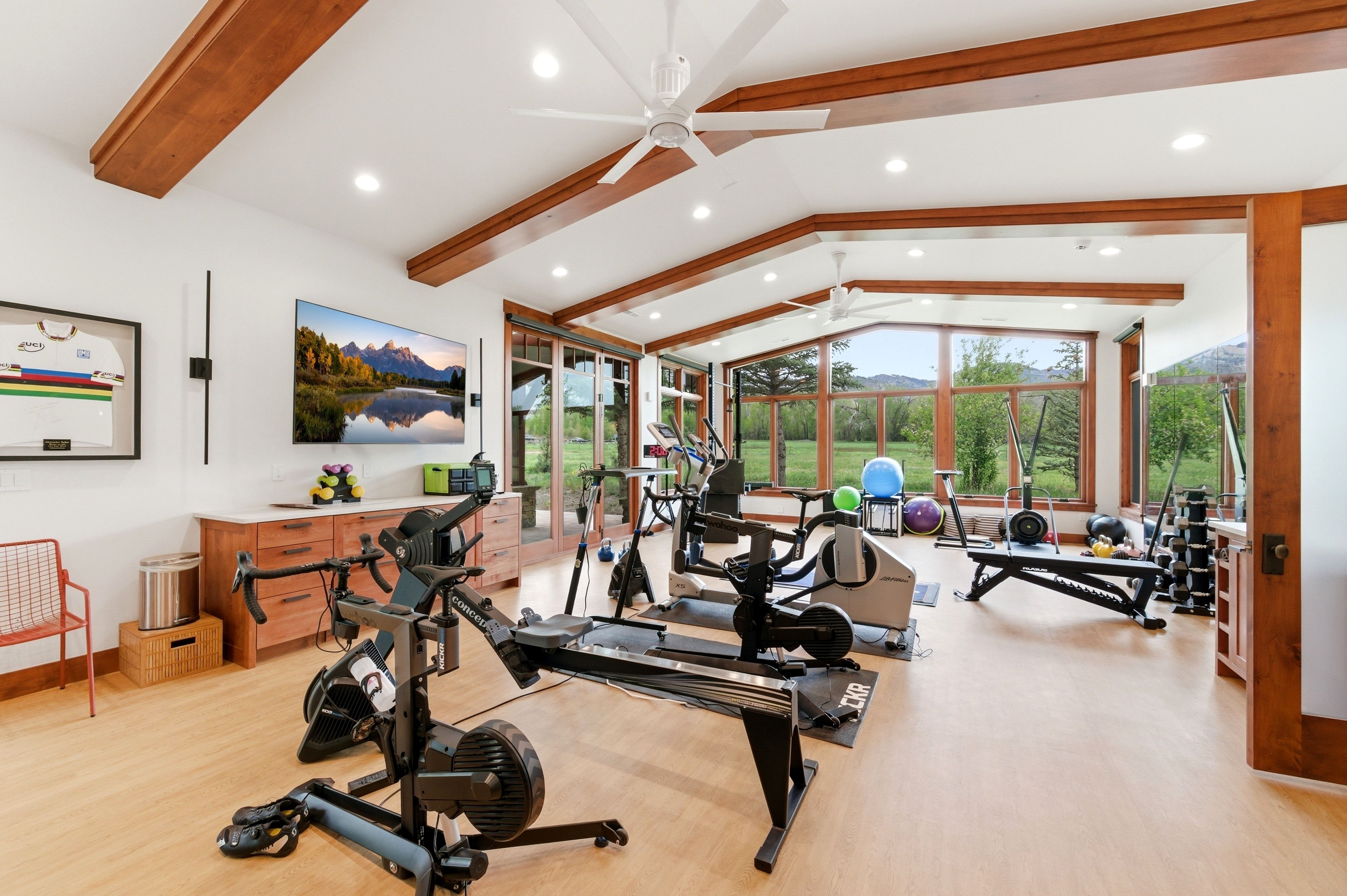 Spacious room featuring vaulted ceilings with exposed wood beams, recessed lighting, and wood-finish flooring