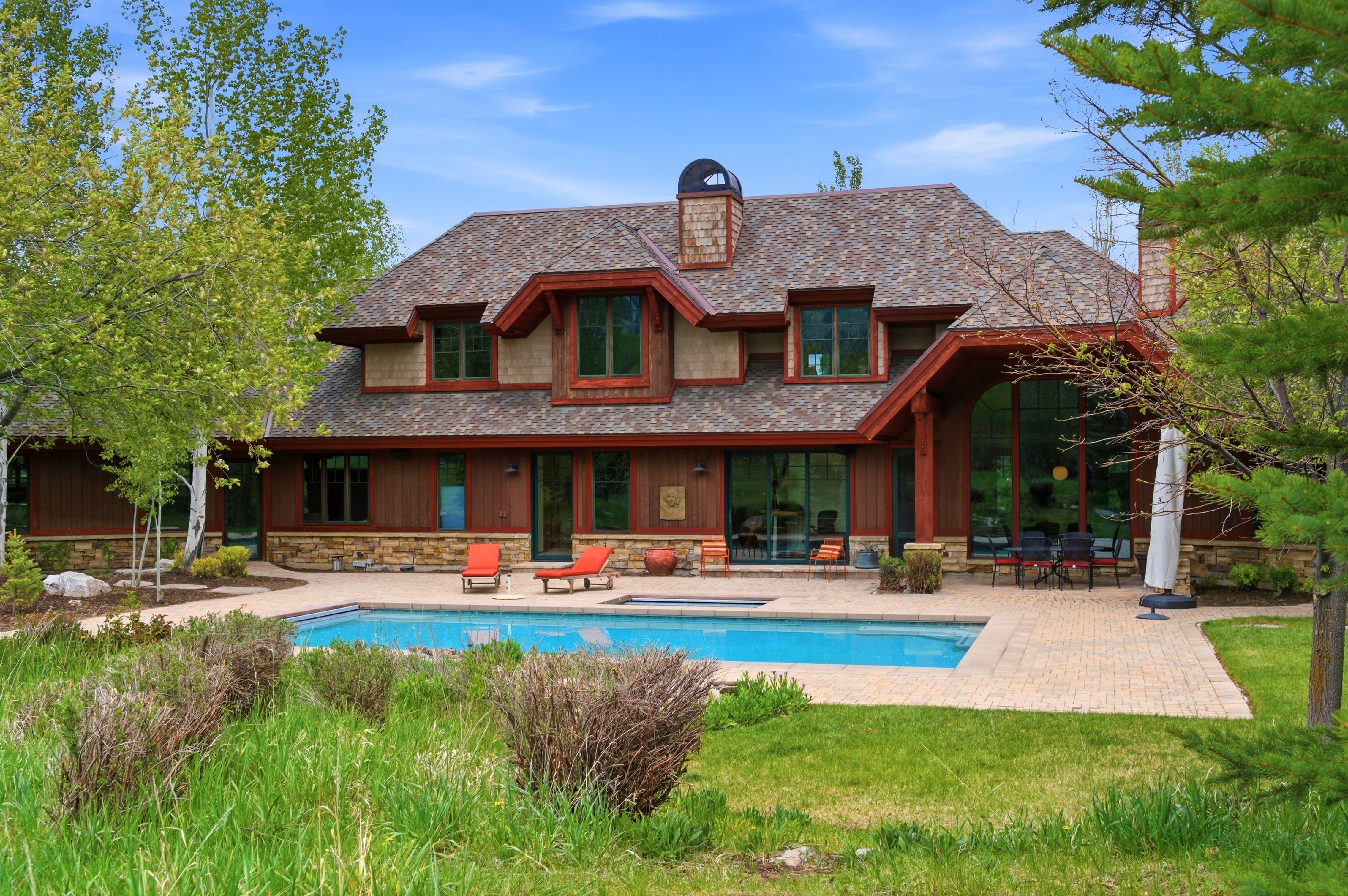 Expansive backyard featuring an inground swimming pool, paver patio, and surrounding natural landscaping