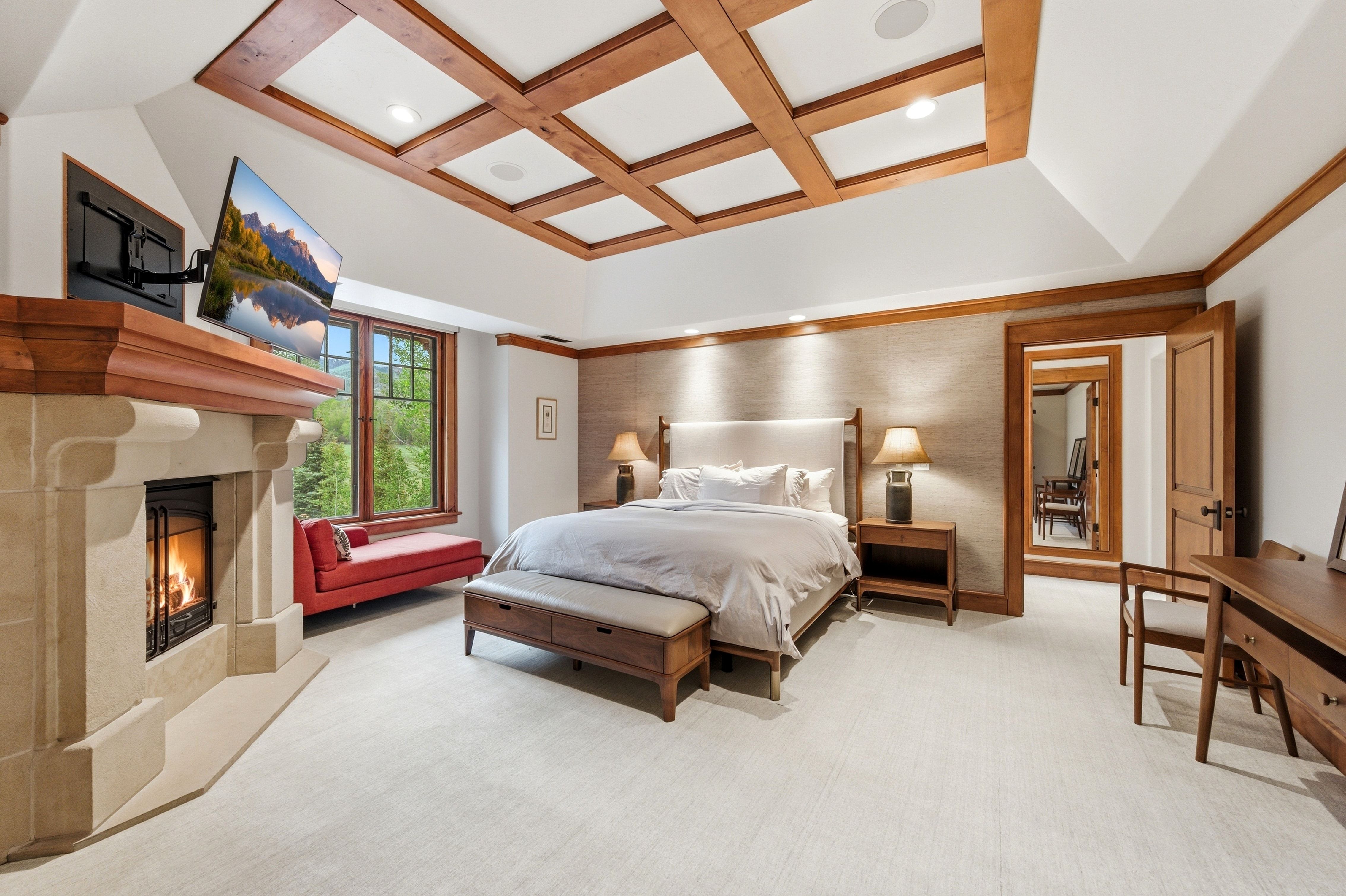 Room featuring a coffered ceiling with wood accents, a stone fireplace, and a large window with multiple panes