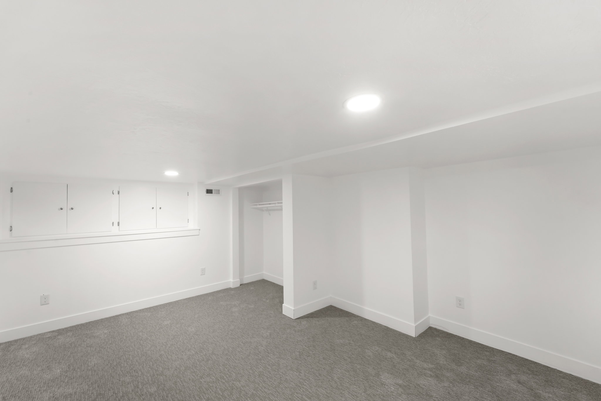 Carpeted interior space featuring white walls and recessed lighting
