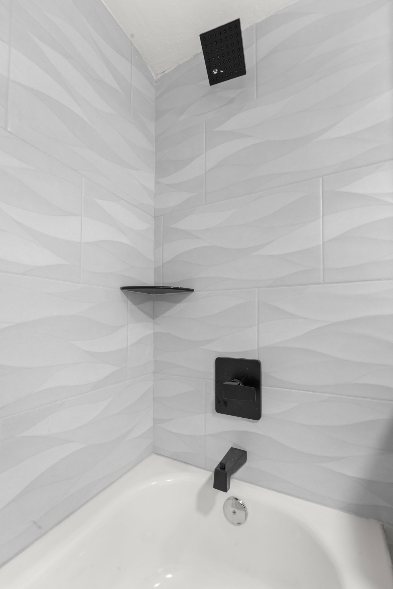 Bathtub with white walls and wave-patterned tile surround