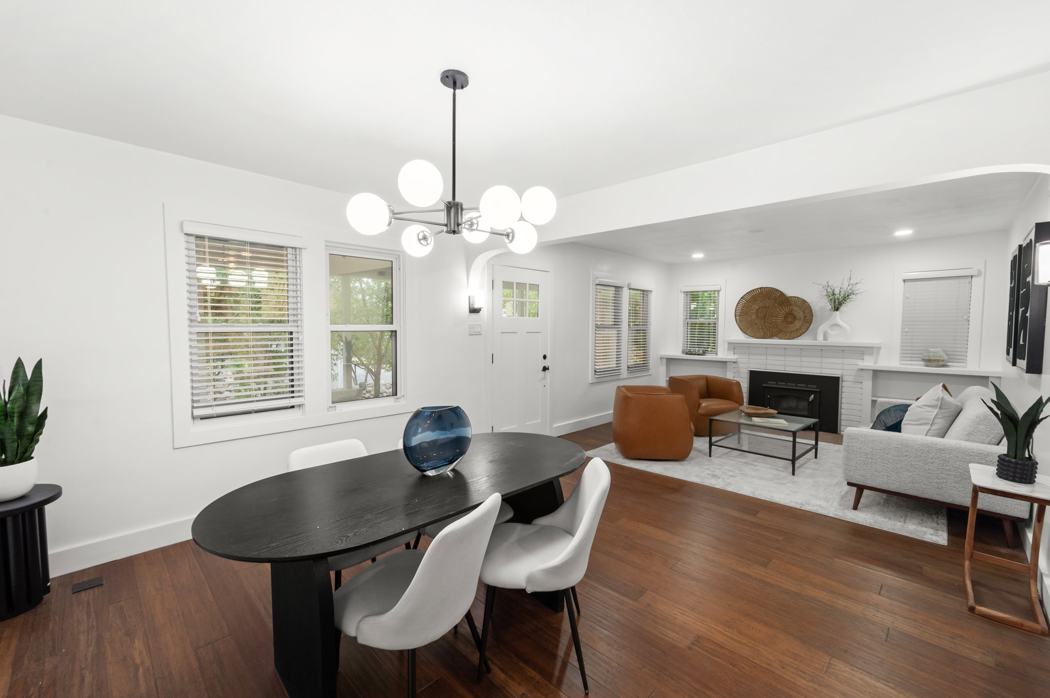 Spacious living area featuring wood-finish flooring, a modern chandelier, and a white-tiled fireplace with built-in shelving