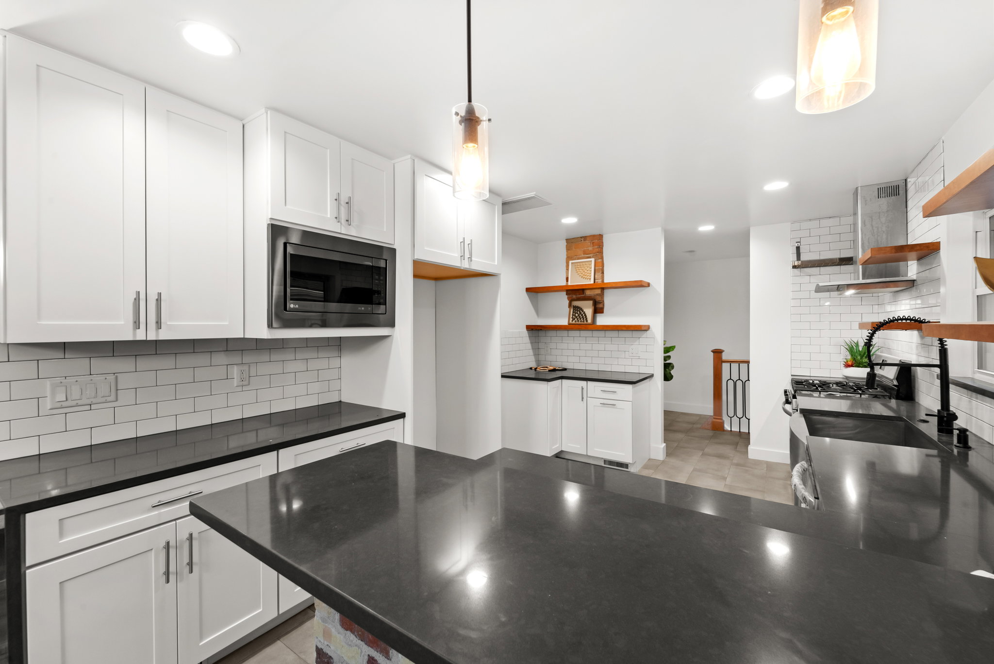 Kitchen featuring a large central island with dark countertops, white shaker cabinetry, subway tile backsplash, and recessed lighting