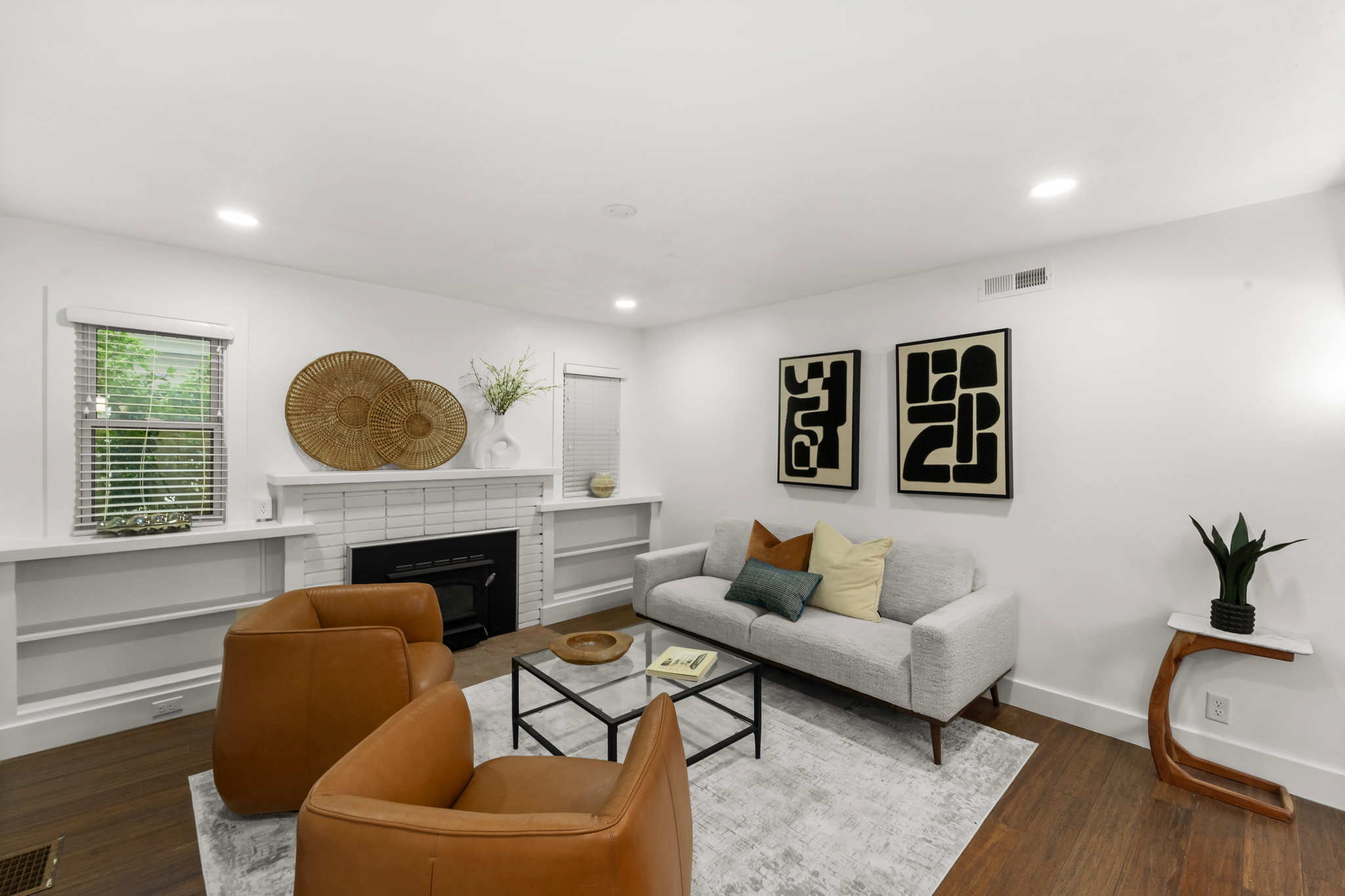 Living area featuring wood-finish flooring, a white brick fireplace with a black insert, recessed lighting, and built-in shelving