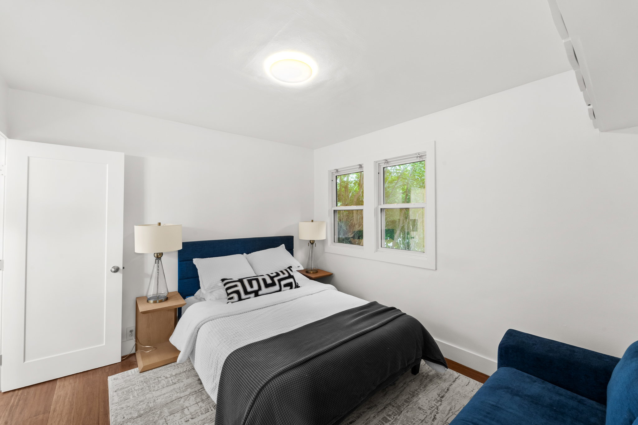 Bright primary bedroom featuring wood-finish flooring and white walls