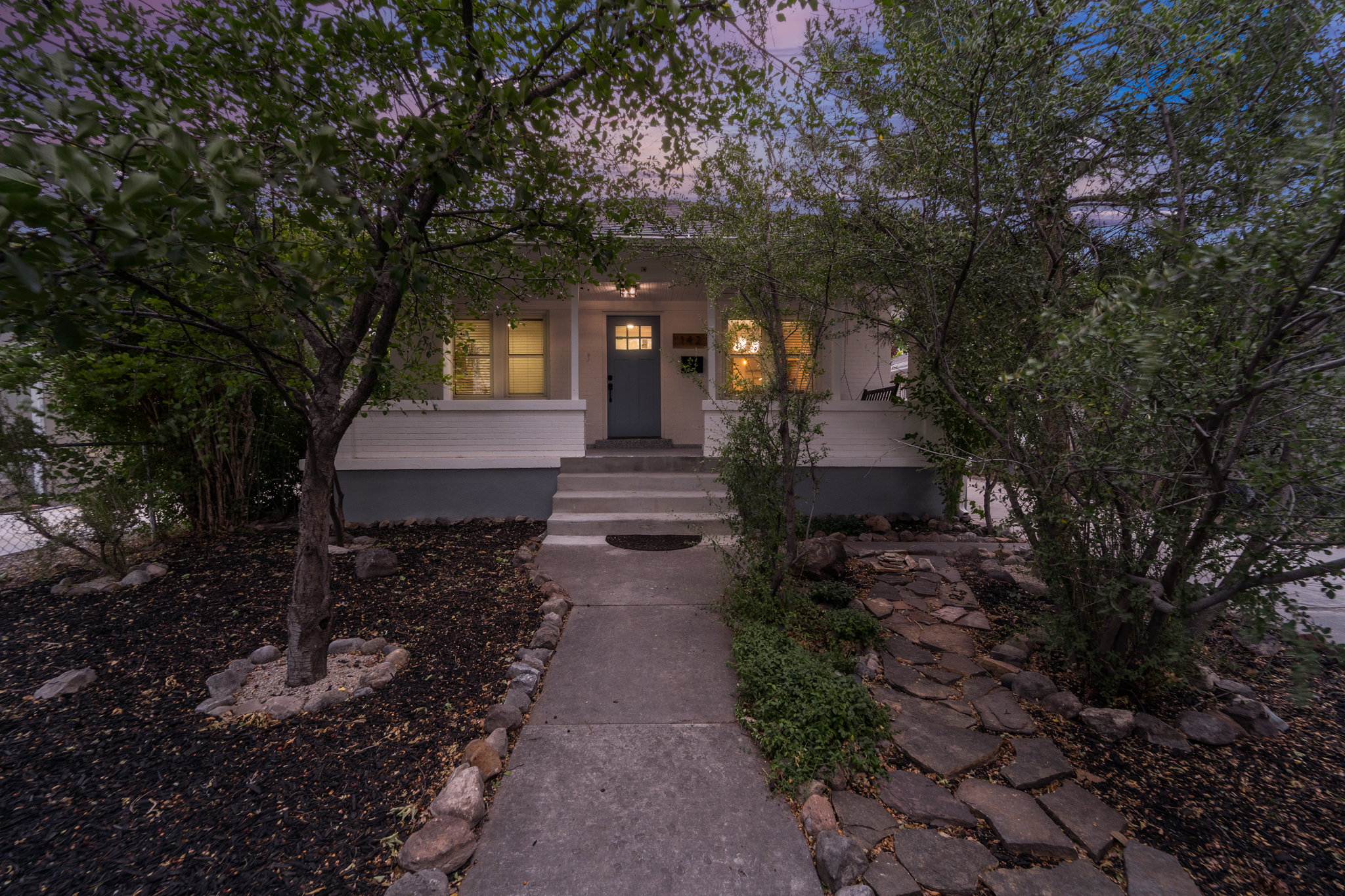 Front facade featuring a welcoming entryway with a dark-paneled door, concrete steps, and a covered porch
