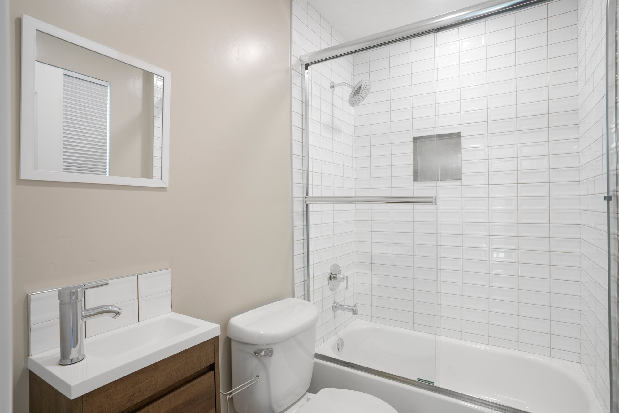 Bathroom featuring a wood-finish vanity with an integrated sink, polished chrome faucet, and white subway tile backsplash