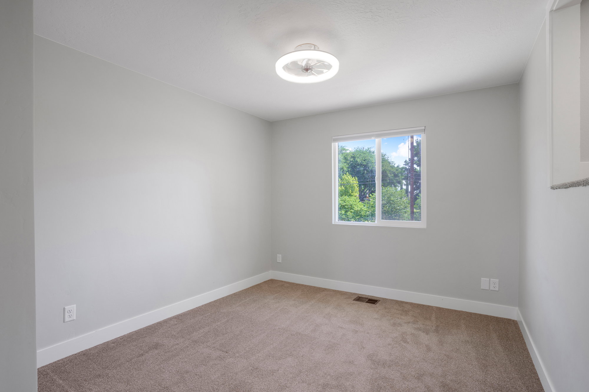 Windowed room with light gray walls and brown carpeting