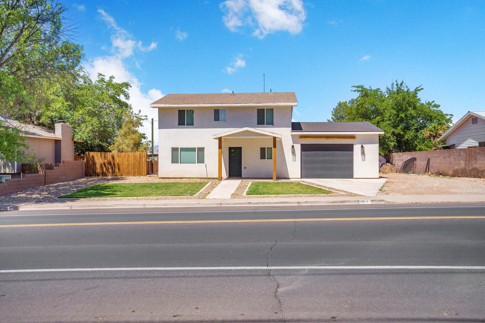 Contemporary two-story residence featuring a smooth stucco exterior and a dark grey garage door