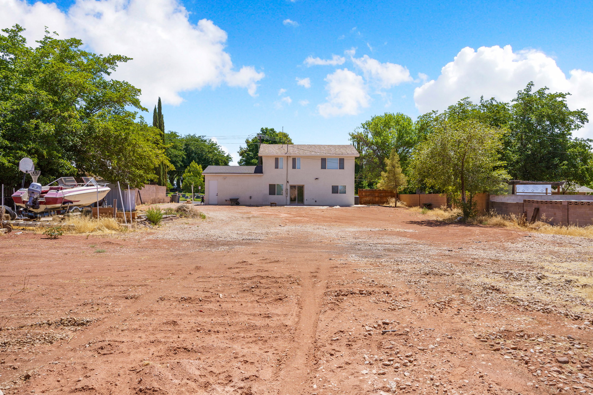 Expansive unpaved lot featuring a two-story residence with a light-colored stucco exterior