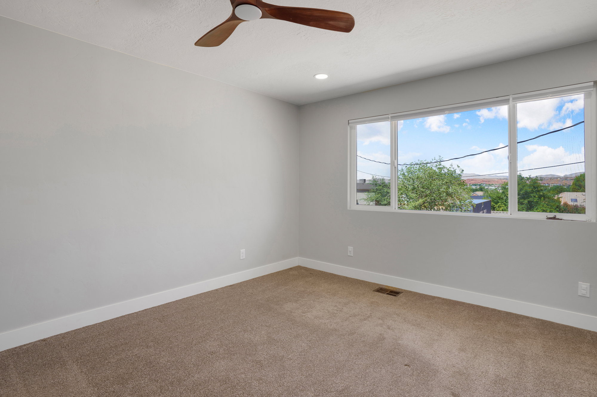 Spacious room featuring neutral carpeting, light gray walls, a contemporary ceiling fan, recessed lighting, and a large window with white trim