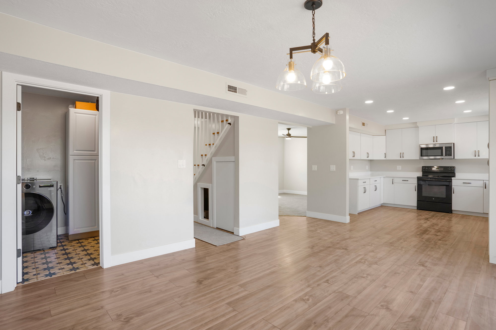 Open-concept living space featuring wood-finish flooring, a modern chandelier, and recessed lighting