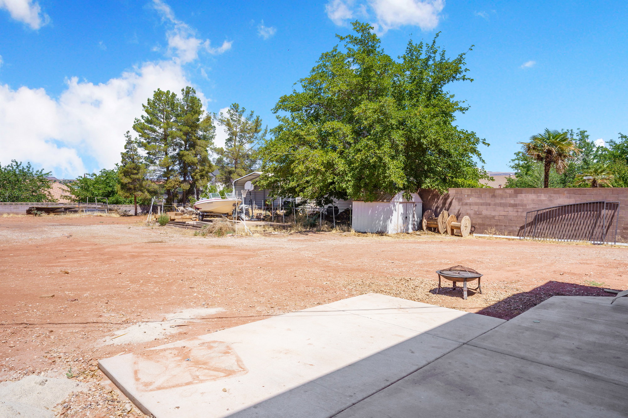 Expansive yard space featuring a concrete patio, a fire pit, and mature trees