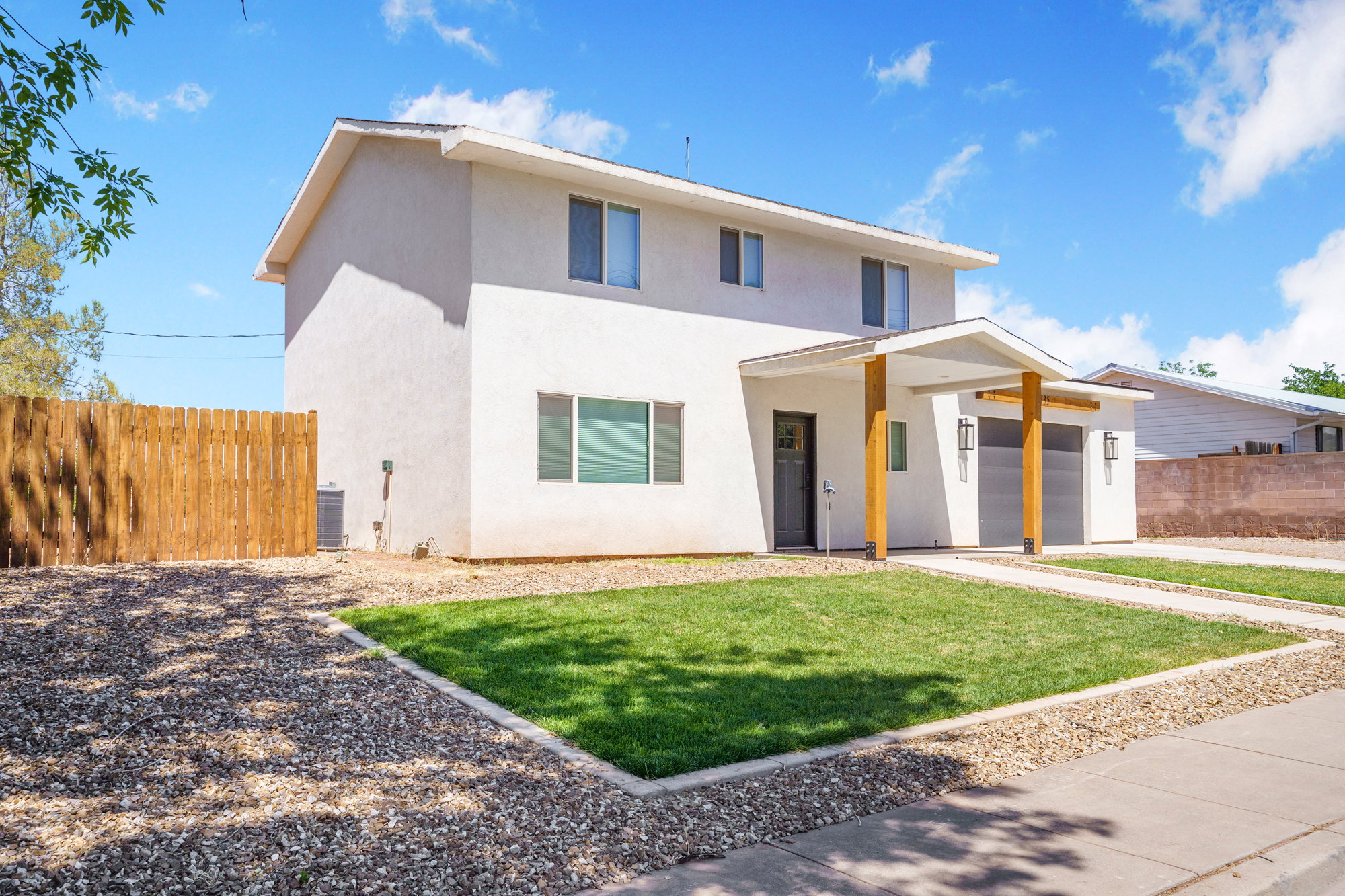 Contemporary white stucco exterior with a covered entry, two-car garage, and wood-toned support beams
